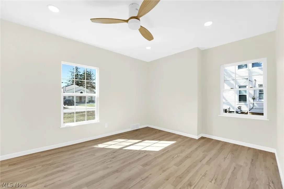 Bedroom: bright room with a ceiling fan, plank flooring, fresh paint and a large window.