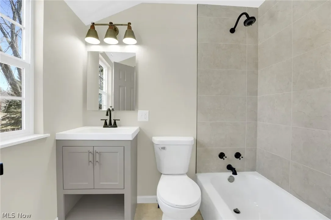 Budget-friendly bathroom remodel: a tiled tub surround, gray vanity and black fixtures show that a fresh look doesn't have to be expensive.