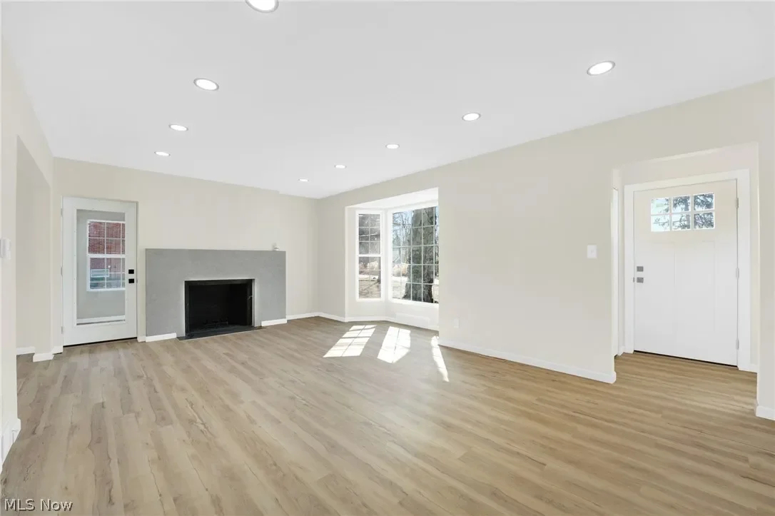 Living room: wood-look plank flooring, recessed lighting and double doors opening to the yard, finished in light neutral paint.