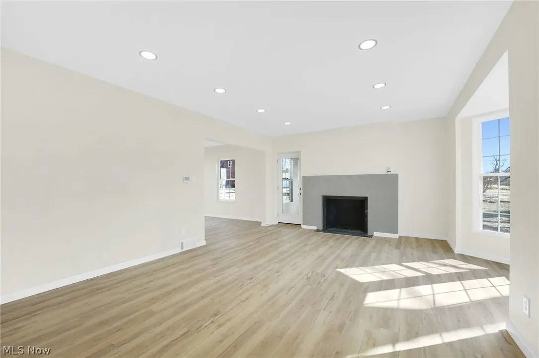 Living room with a modern fireplace: gray fireplace surround, plank flooring and recessed lighting.