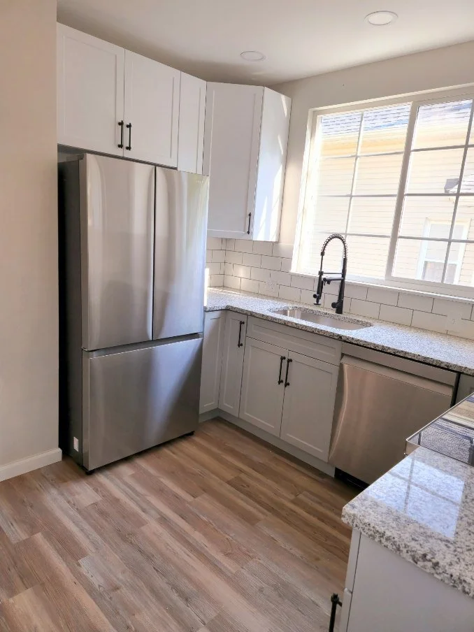 Kitchen: sink wall with white and gray two-tone cabinetry, a window over the sink and a stainless steel refrigerator.