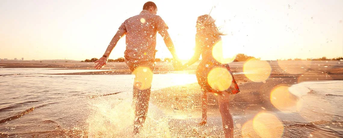 A couple walking through sunlit surf — original Jesus Is For You banner