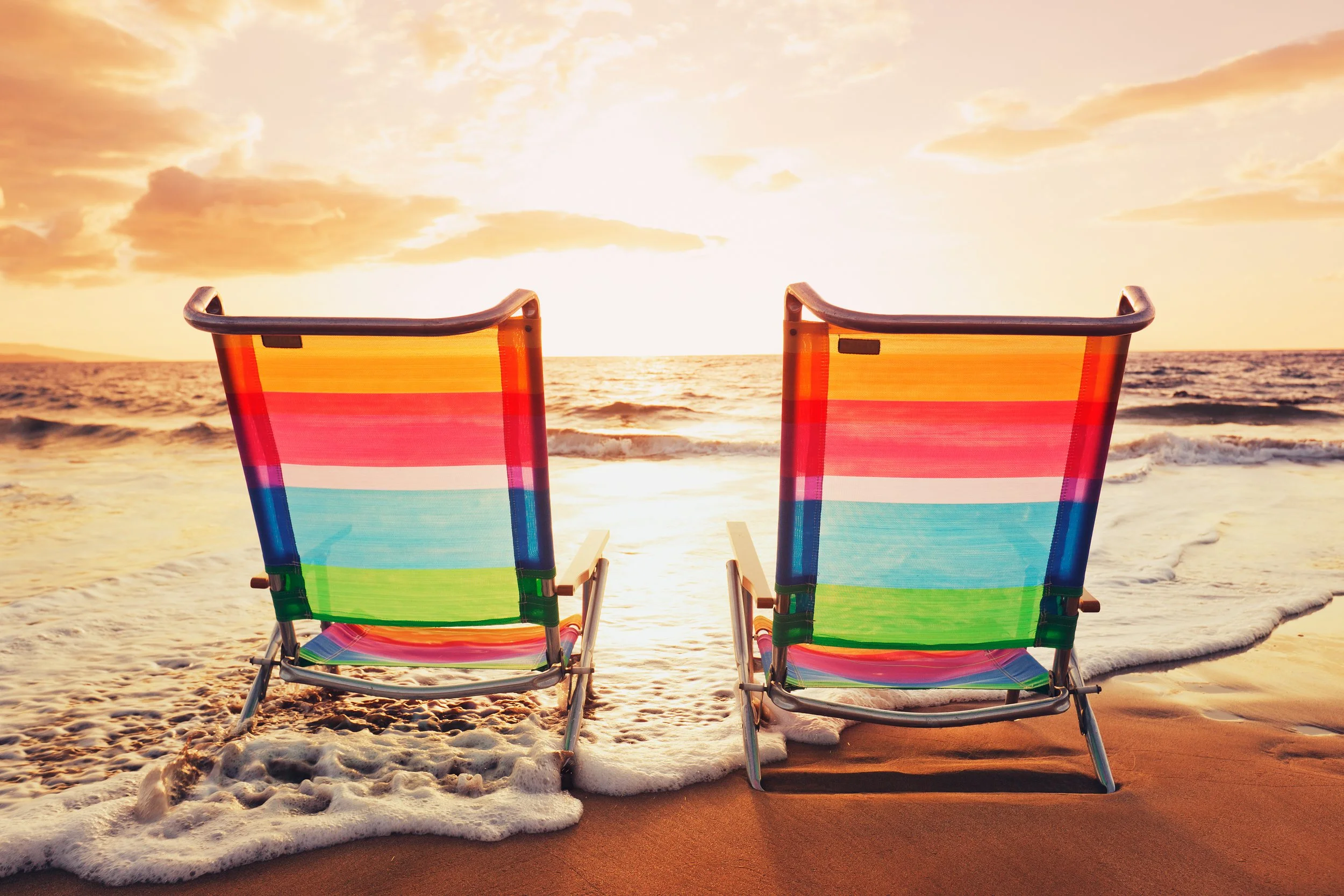 Two beach chairs facing the ocean at sunset
