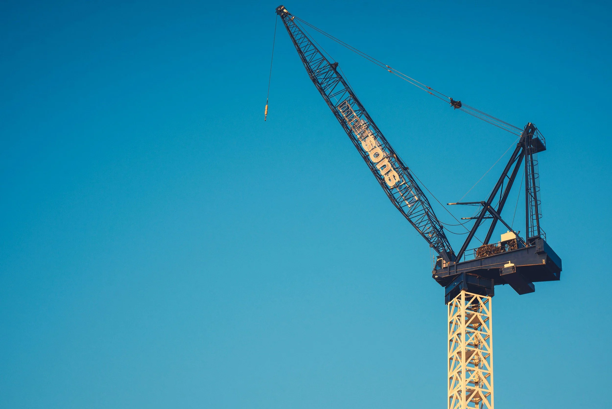 A tall construction crane set against a clear blue sky.