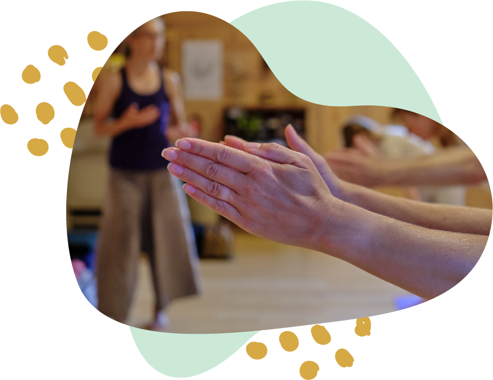 Group of people practicing yoga or meditation with hands pressed together in a prayer position in a studio.