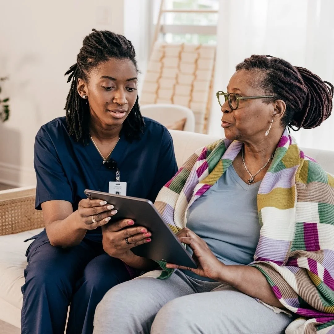 Une femme médecin parle à une femme âgée en leur montrant quelque chose sur une tablette.