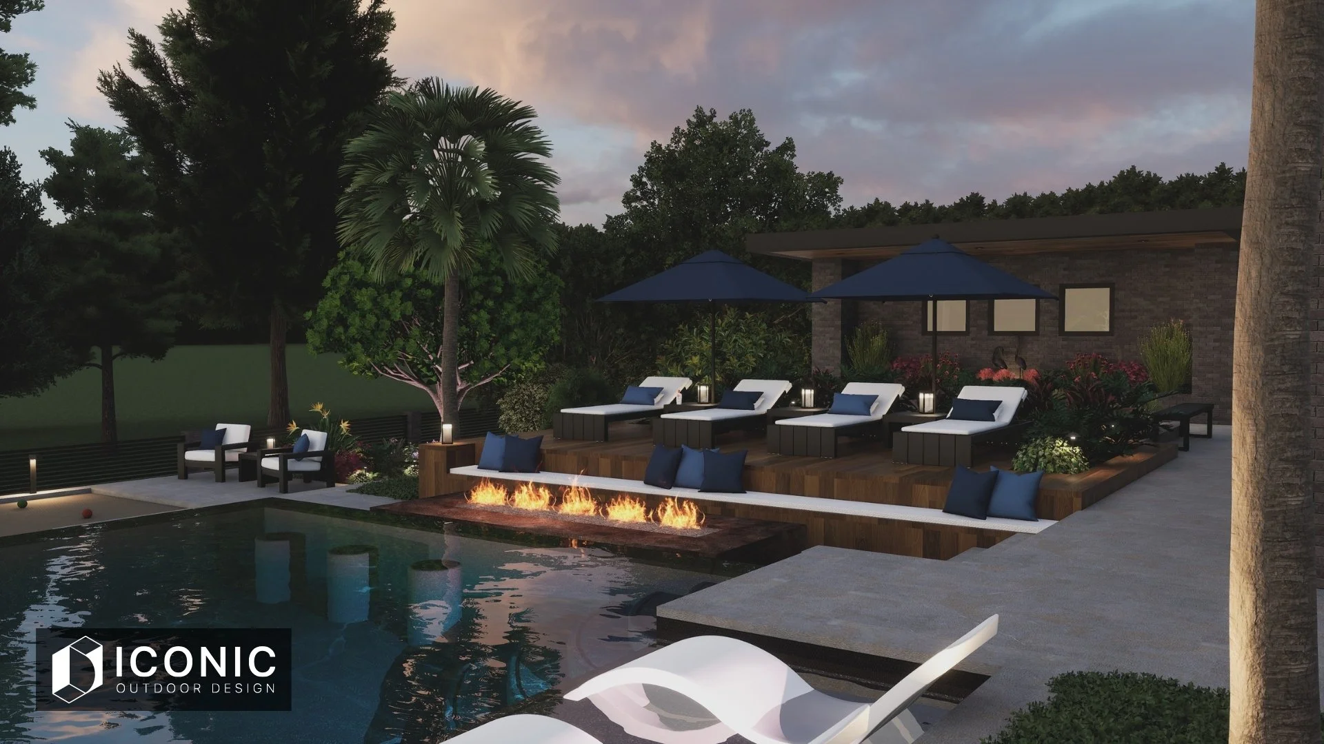 Backyard pool area with lounge chairs and umbrellas, a fire feature, outdoor seating, trees, and a modern house with a brick wall at dusk.