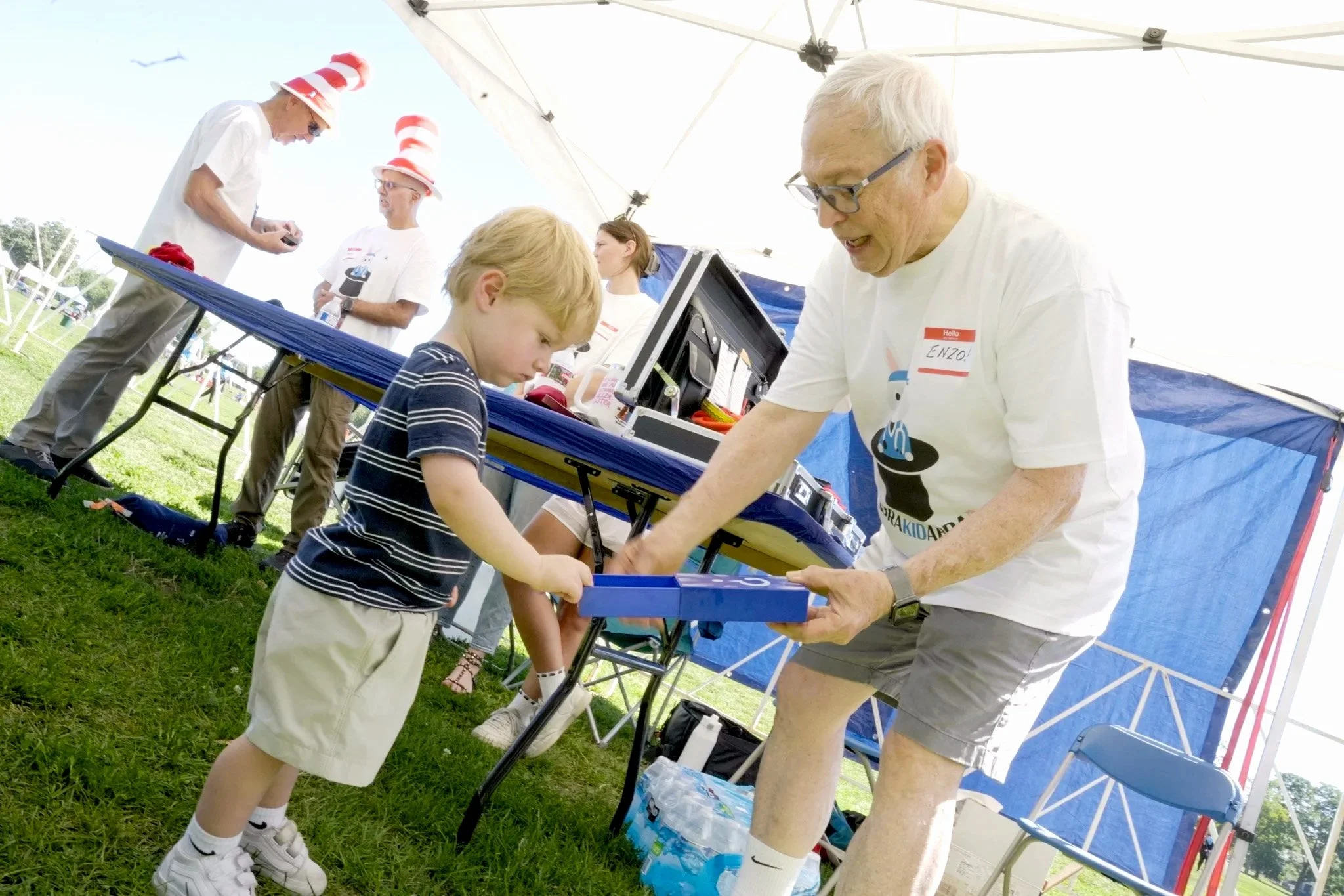 A fundraiser event where A young boy and a Volunteer Magician engage in a magic trick. Both smiling at the magic.