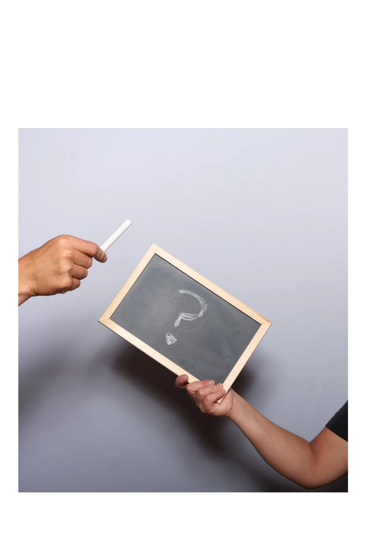 Two people holding a small chalkboard with a question mark drawn on it and a piece of chalk. Taken by Nook booth Photo Booth.