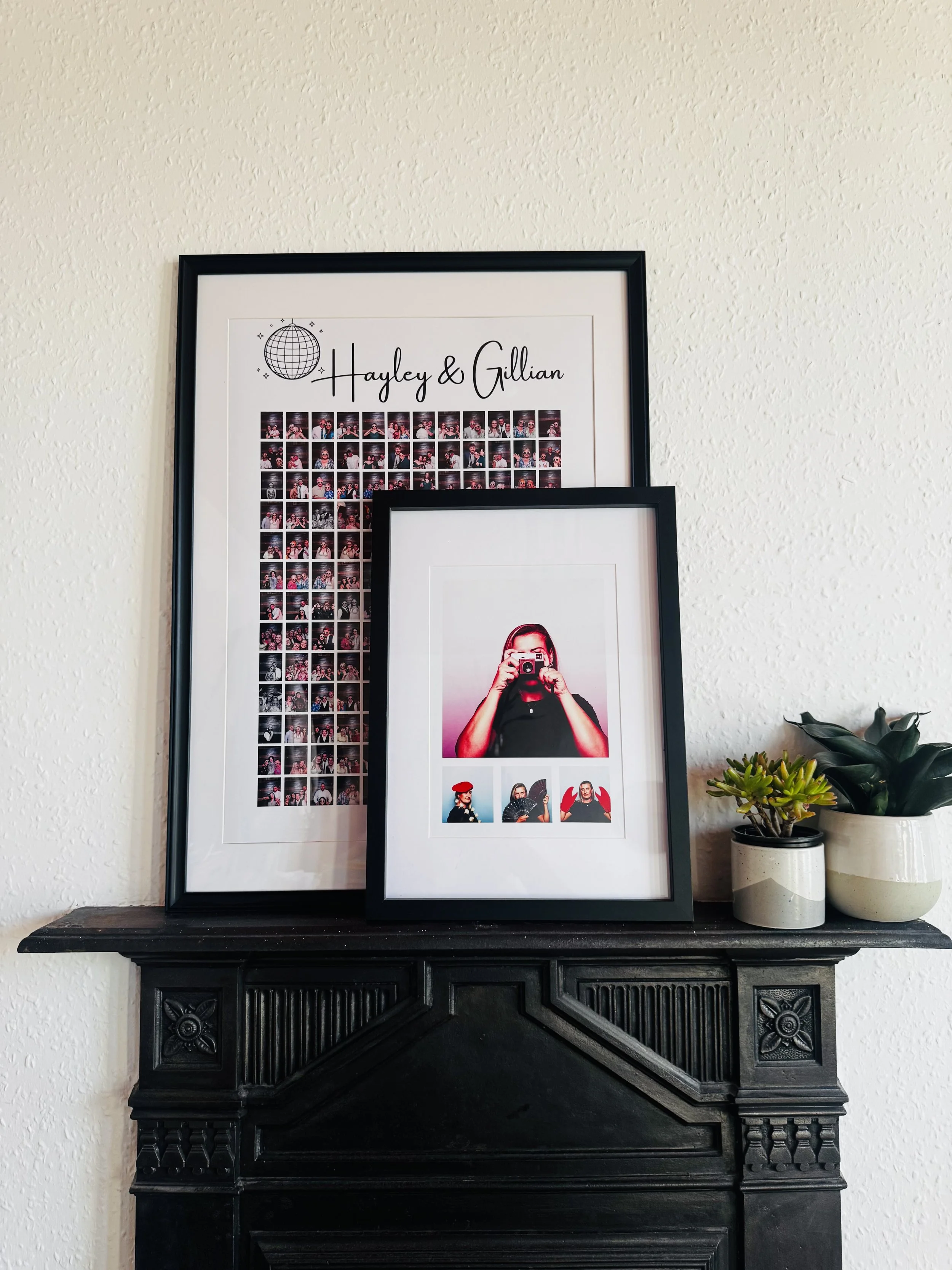 A black fireplace mantel with 2 framed photos and a small collection of potted plants. One framed photo features a woman taking a picture with a camera, and the other contains a collage of smaller images and the names Hayley & Gillian. Nook Booth