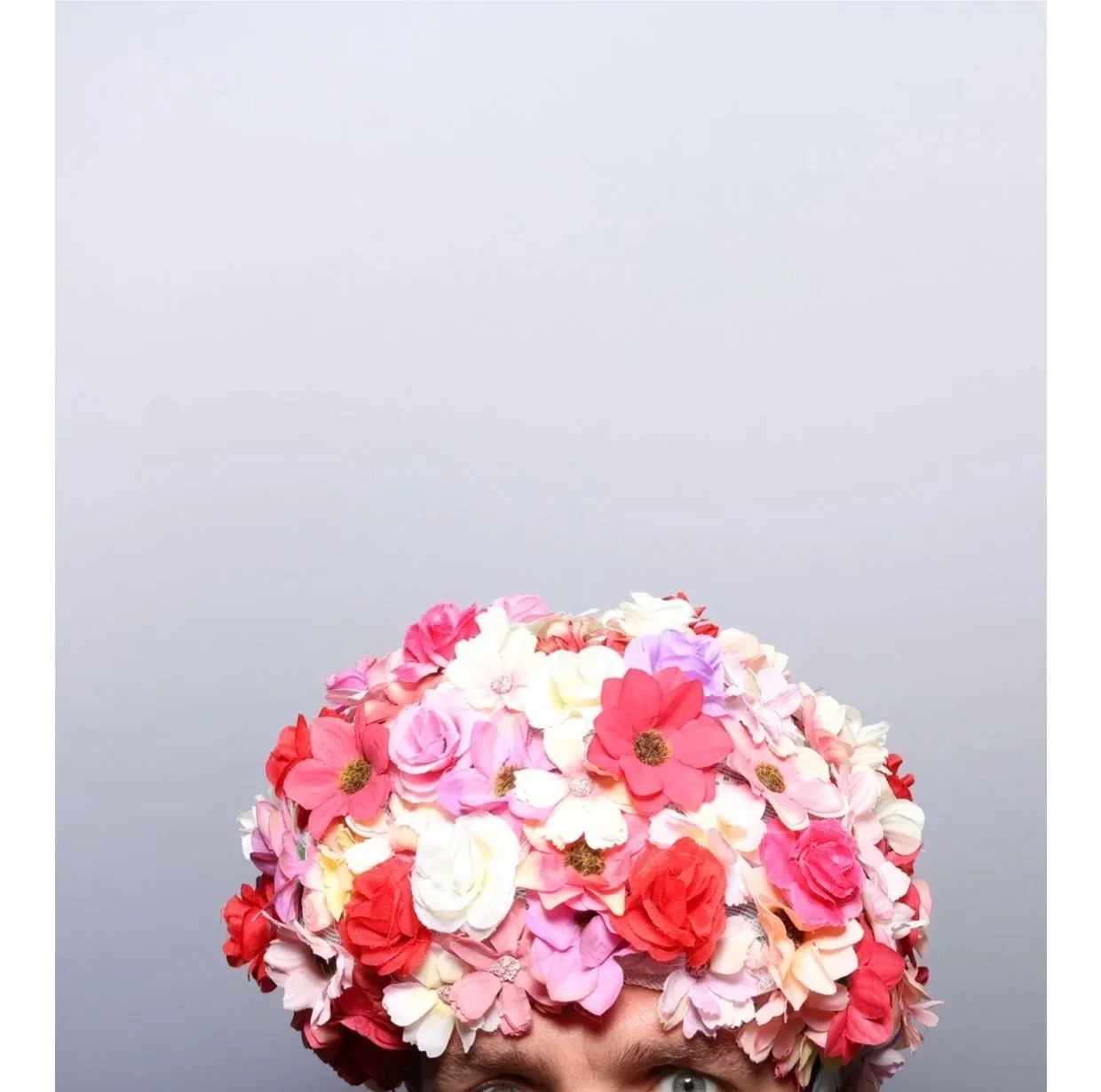 Person wearing a floral headpiece with pink, red, white, and purple flowers.