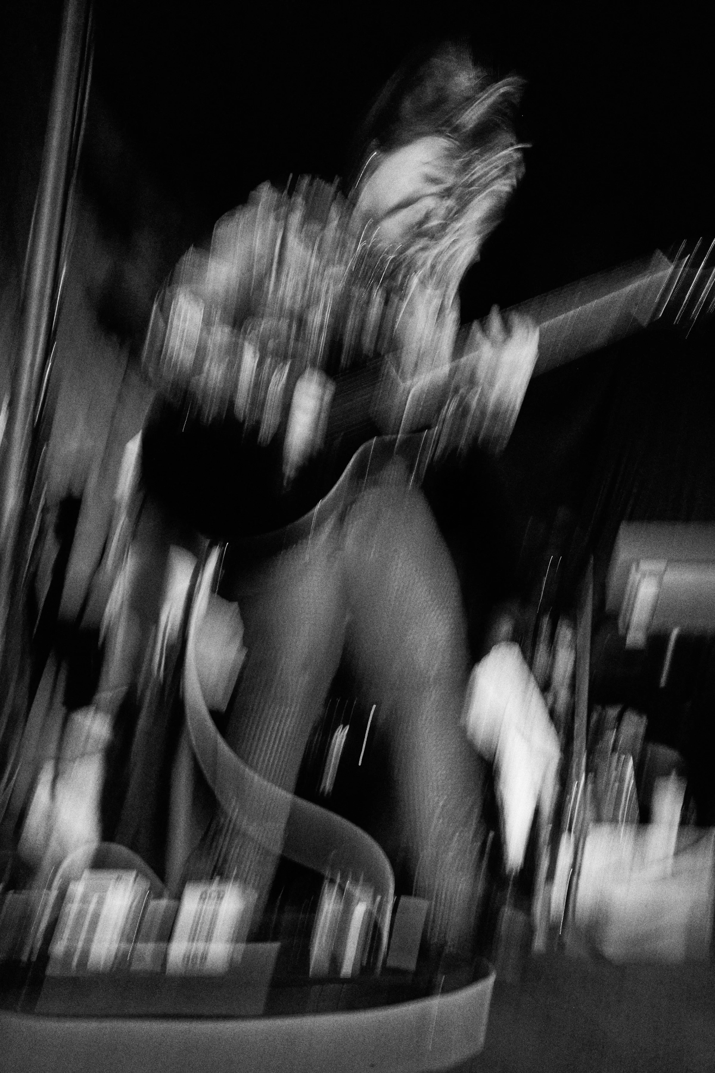 A distorted image of a woman playing a seven string guitar.
