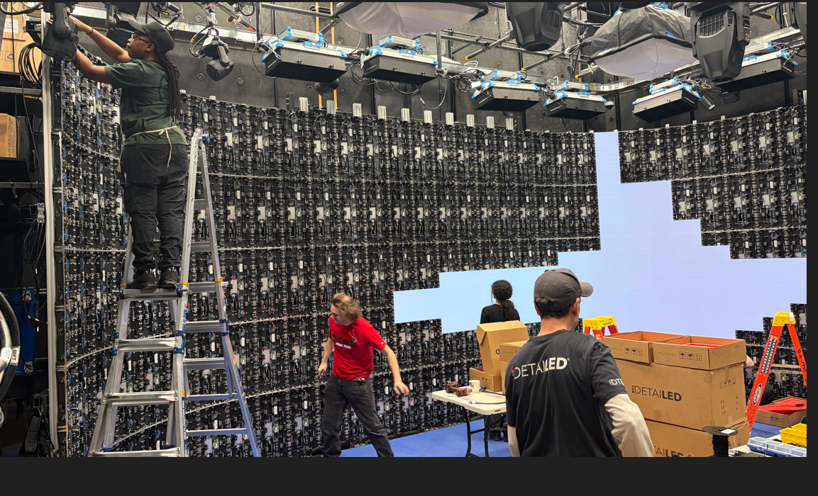 People working on assembling a large LED display wall with multiple people installing or maintaining the setup in a studio or workspace. New York City, Television Production 