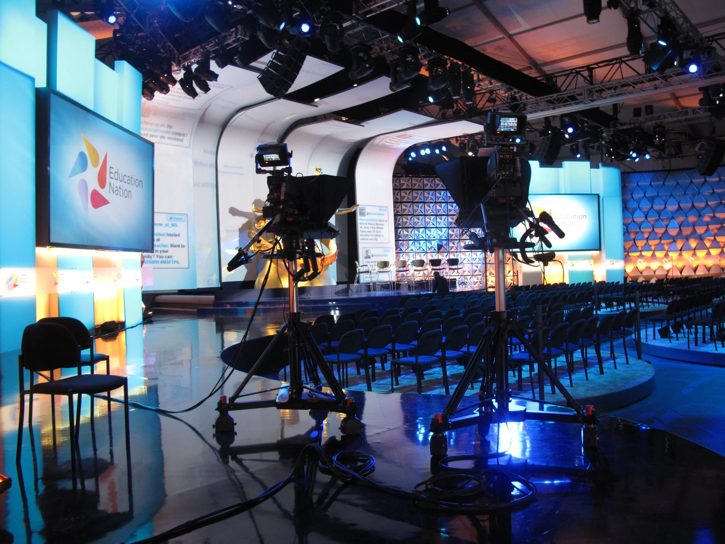 Stage set for an Education Nation event with large screens displaying the logo, stage chairs, camera equipment, and lighting. NBC, 30 Rockefeller Plaza, New York City, NYC