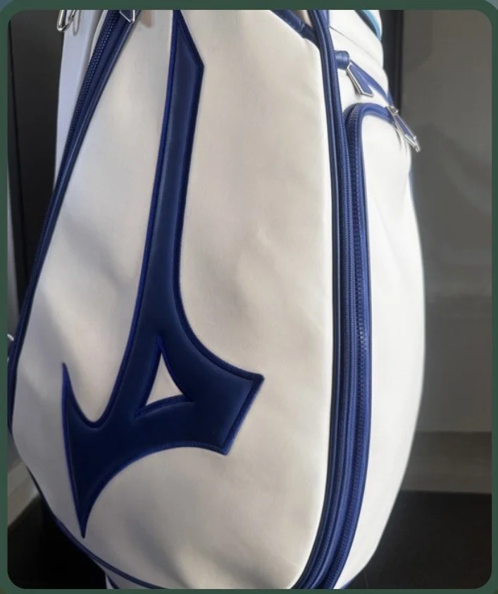 Close-up of a white sports bag with blue zipper accents and a large blue logo on the side.