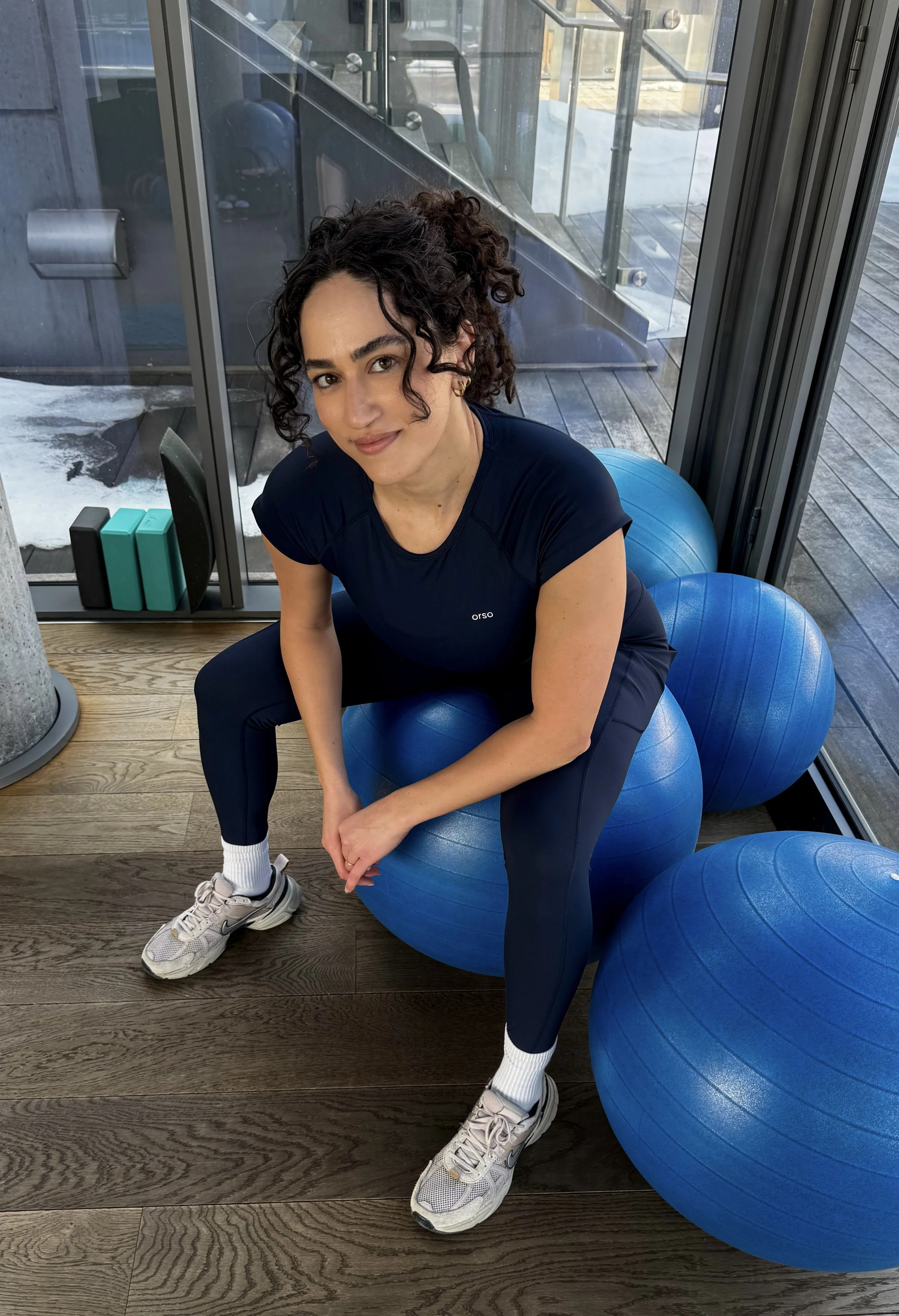 Prenatal & Postpartum Personal Trainer - Woman - Sitting on a blue ball at the gym