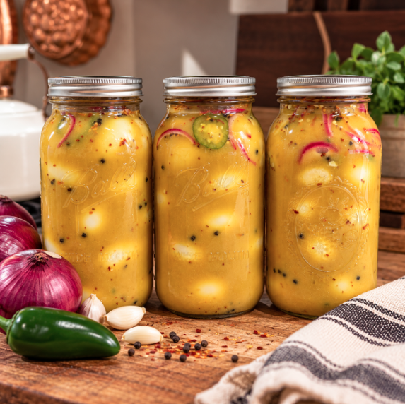 Honey mustard pickled eggs with onion and jalapeño packed in a glass Mason jar with golden mustard brine.