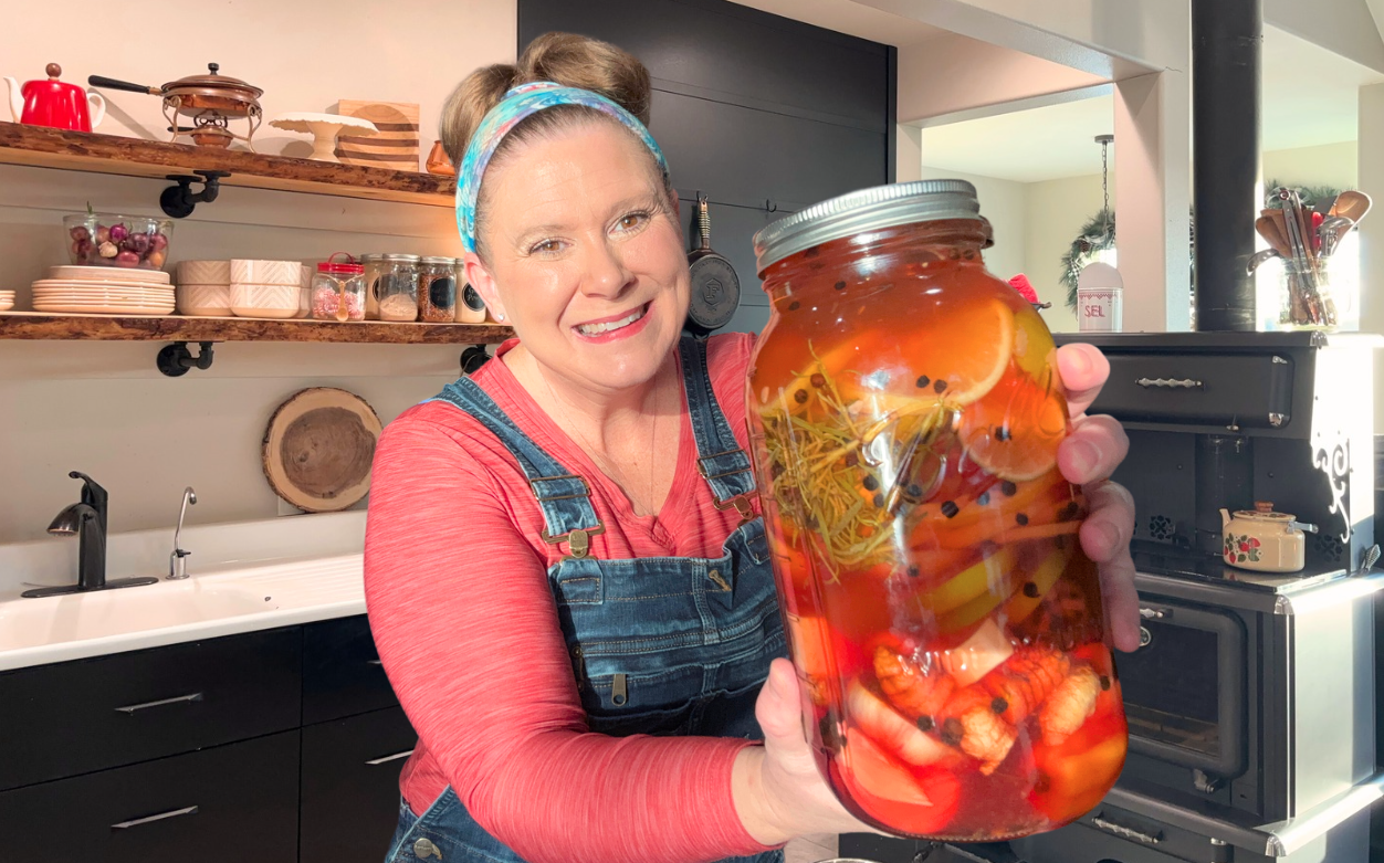 Jessica holding a jar of homemade Alaskan fire cider in her kitchen