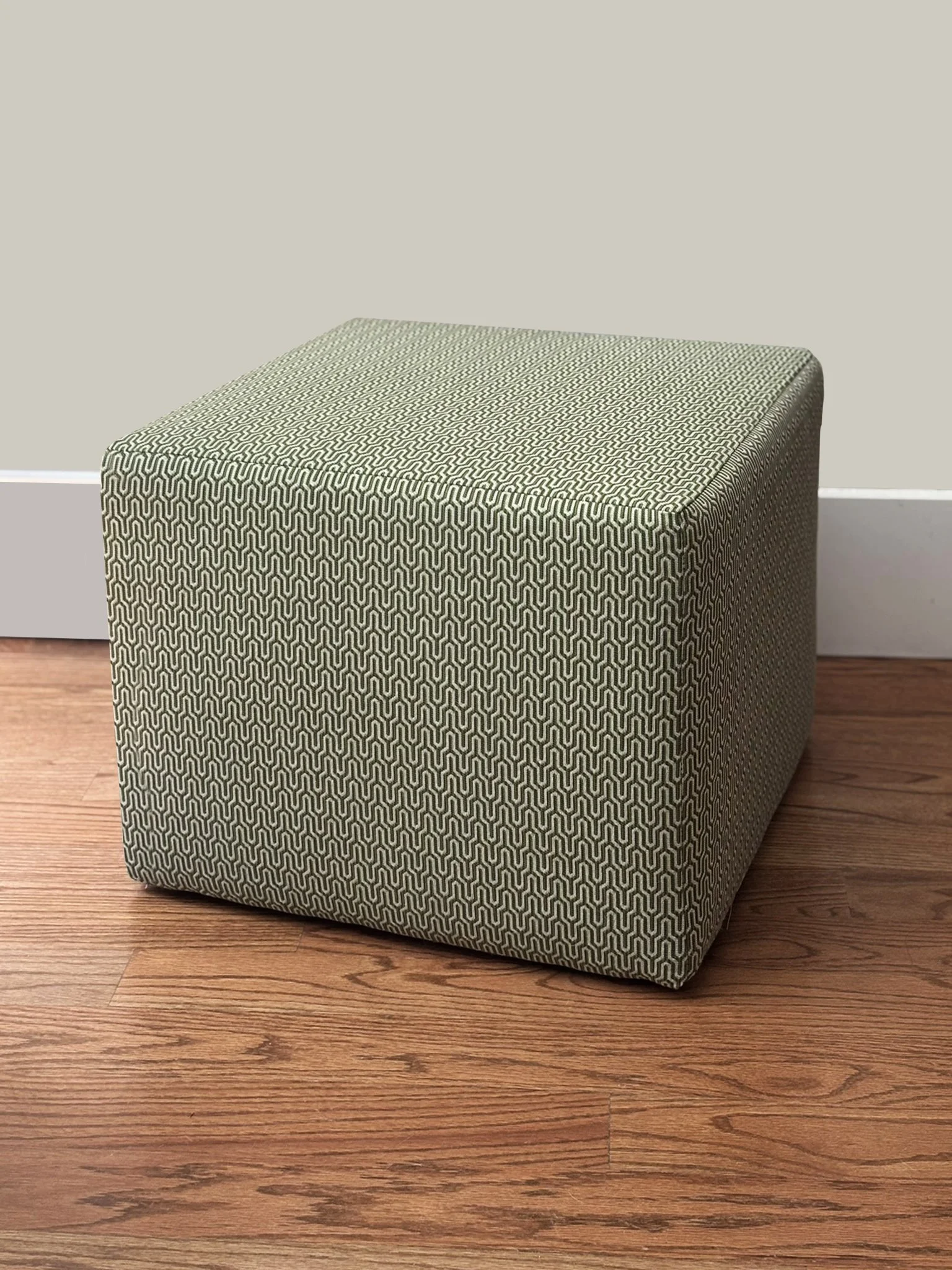 Patterned upholstered cube ottoman on a hardwood floor