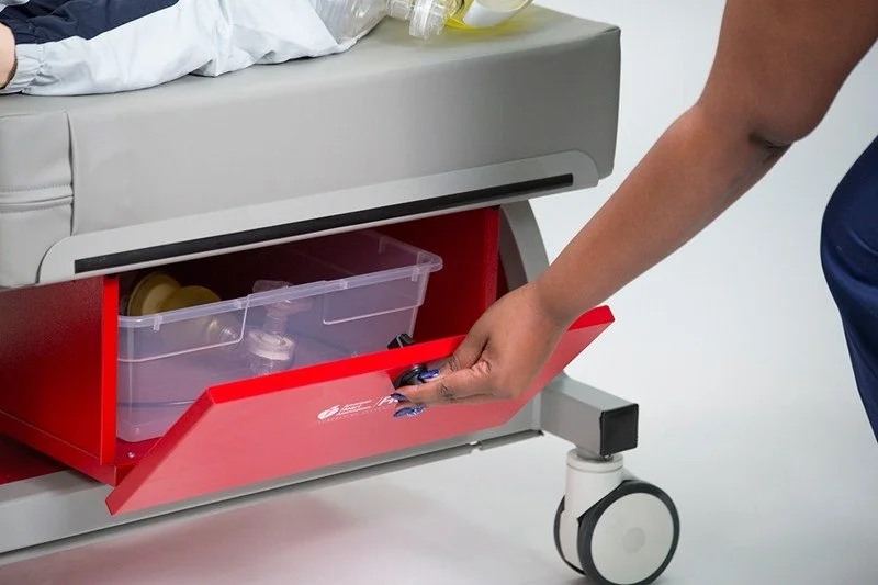 Healthcare worker opening a red drawer on a medical cart stocked with supplies