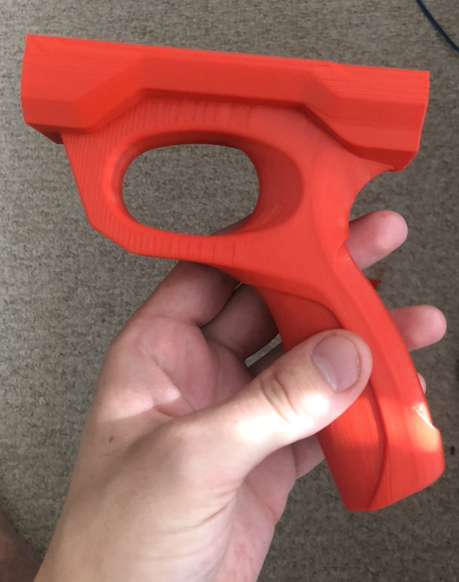 Red plastic toy gun held in a person's hand over a carpeted floor