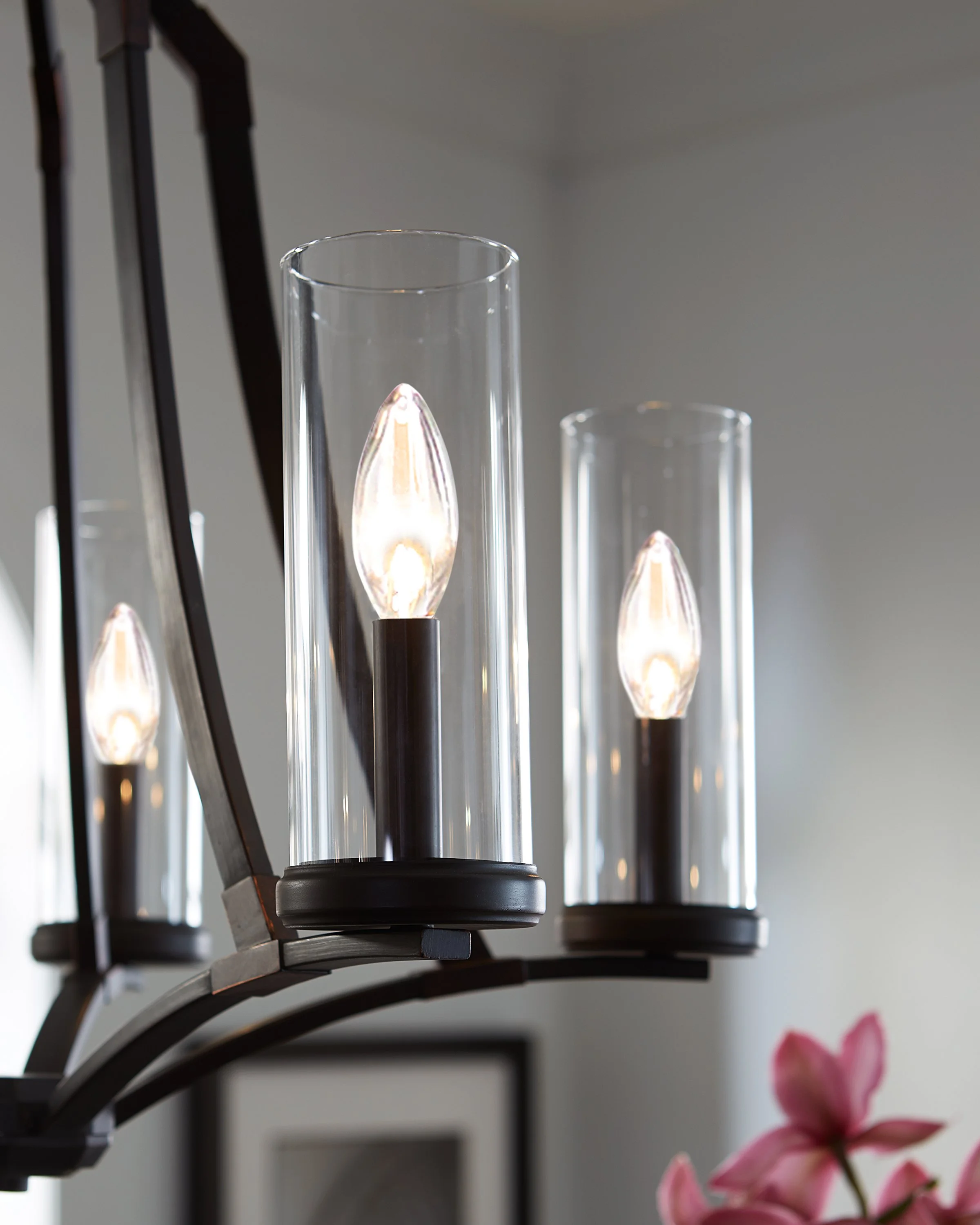 Close-up of modern black pendant lights with glowing candle-shaped bulbs in clear glass cylinders
