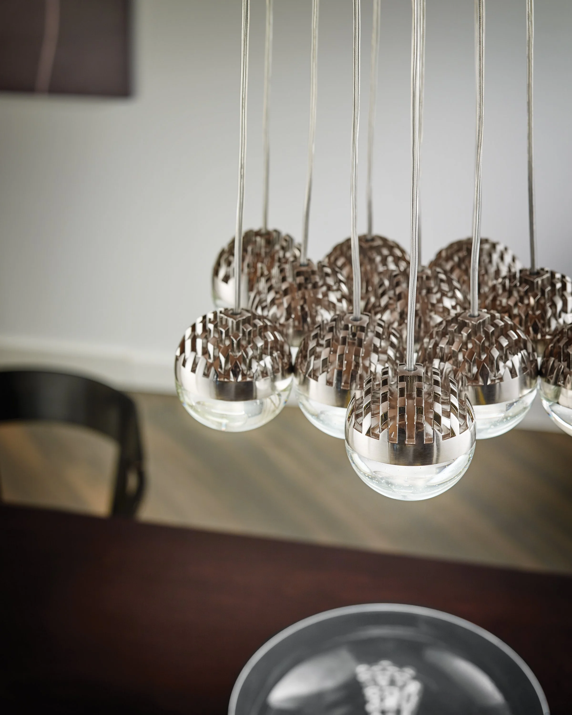 Close-up of modern silver pendant lights with textured metal shades and clear glass globes