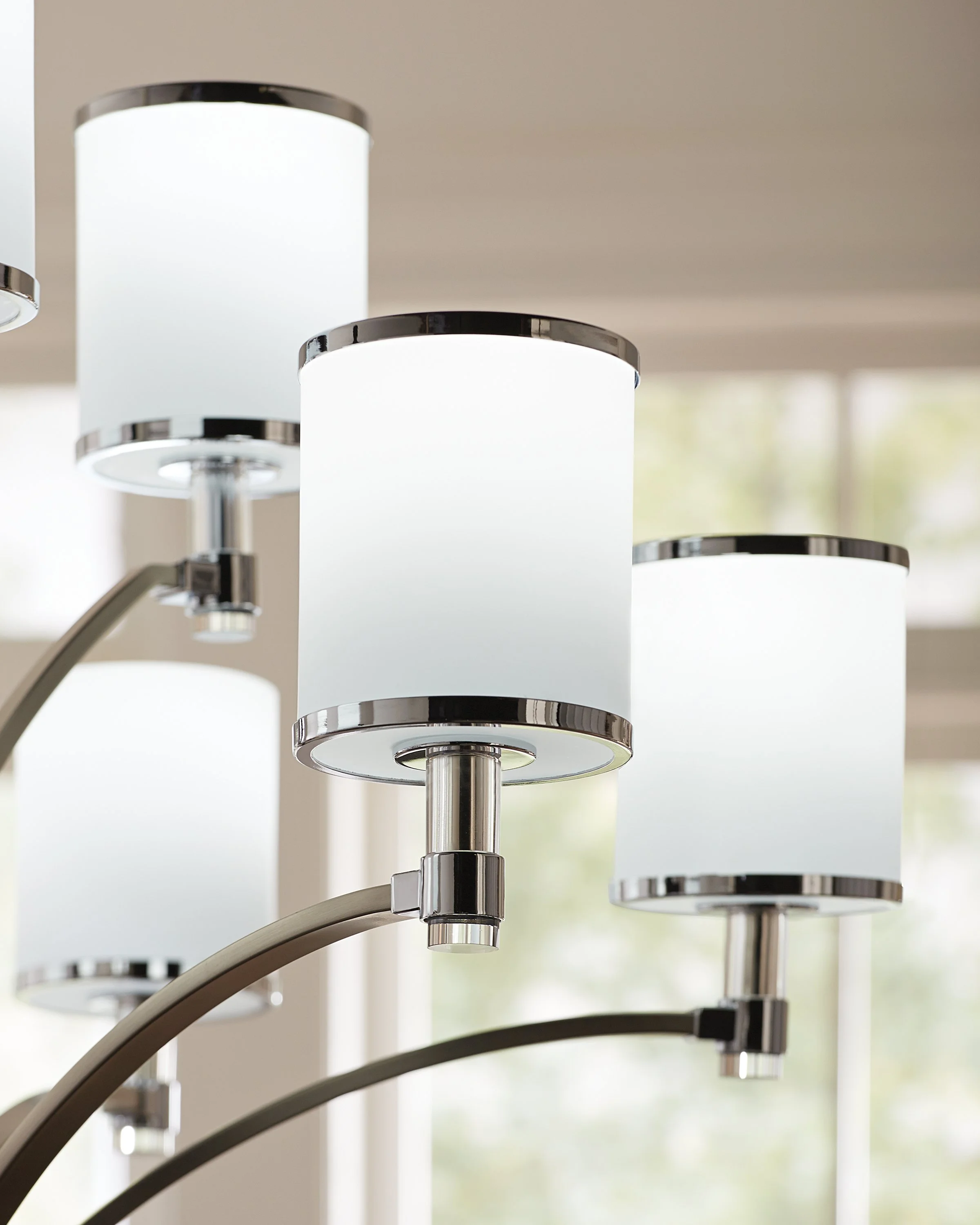Close-up of modern pendant lights with white cylindrical shades and chrome accents