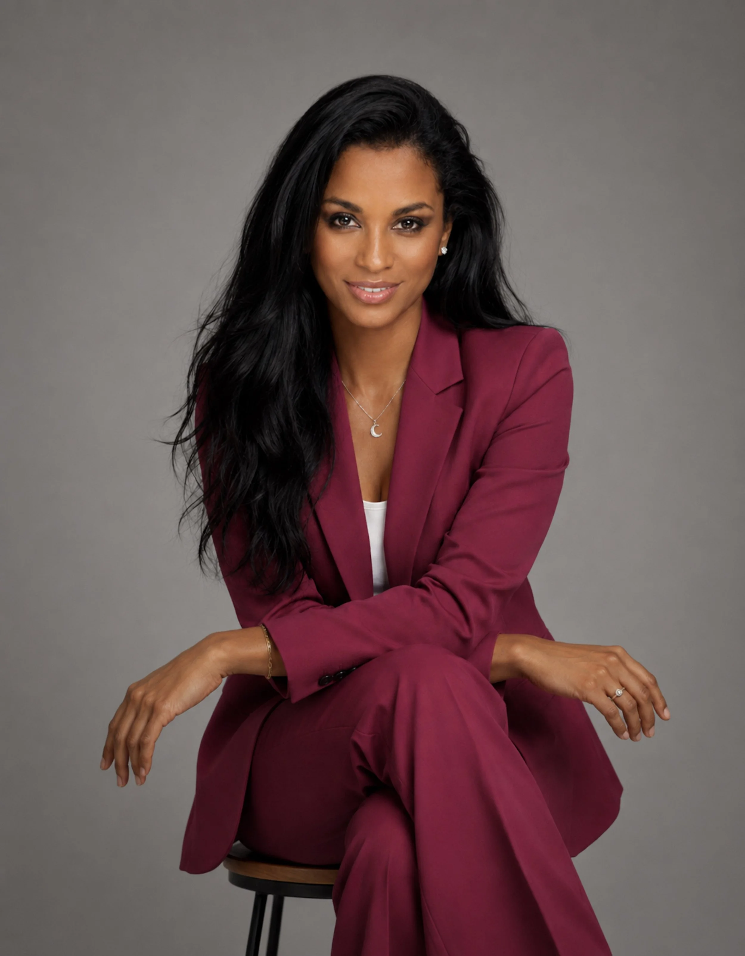 Portrait of Jasmine Glass, photographer behind Remote Photoshoots, wearing a raspberry suit against a neutral studio background.