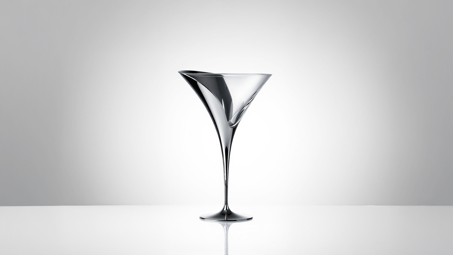 Tulip Martini glass by Pheiffer — a mirror-polished chrome cocktail glass with a flared, asymmetric tulip-shaped bowl and slender tapered stem, shown against a soft grey studio backdrop.