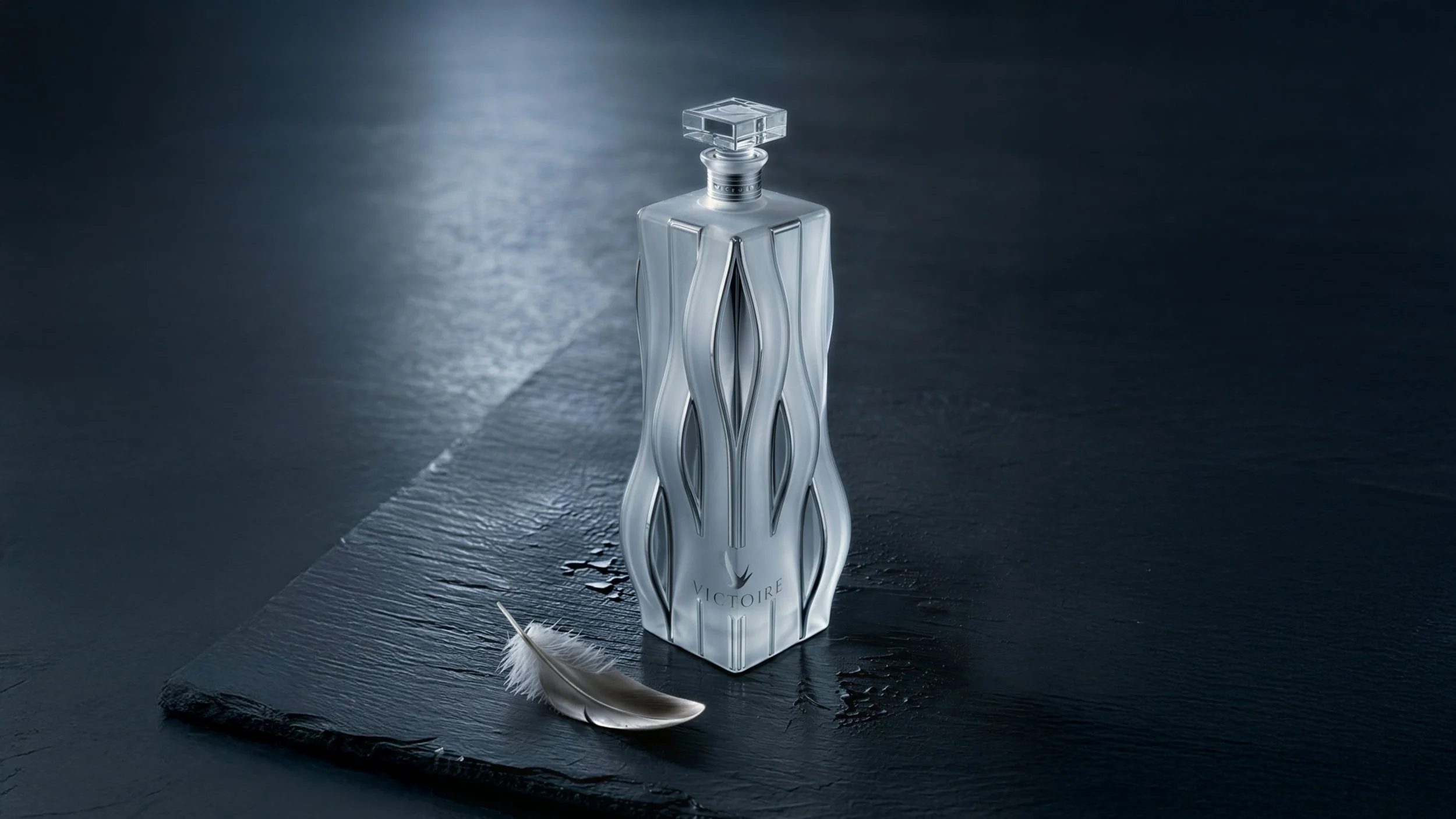 Victoire bottle concept proposal by Pheiffer — the frosted sculpted vodka bottle lit on dark wet slate, with a single feather resting beside it.
