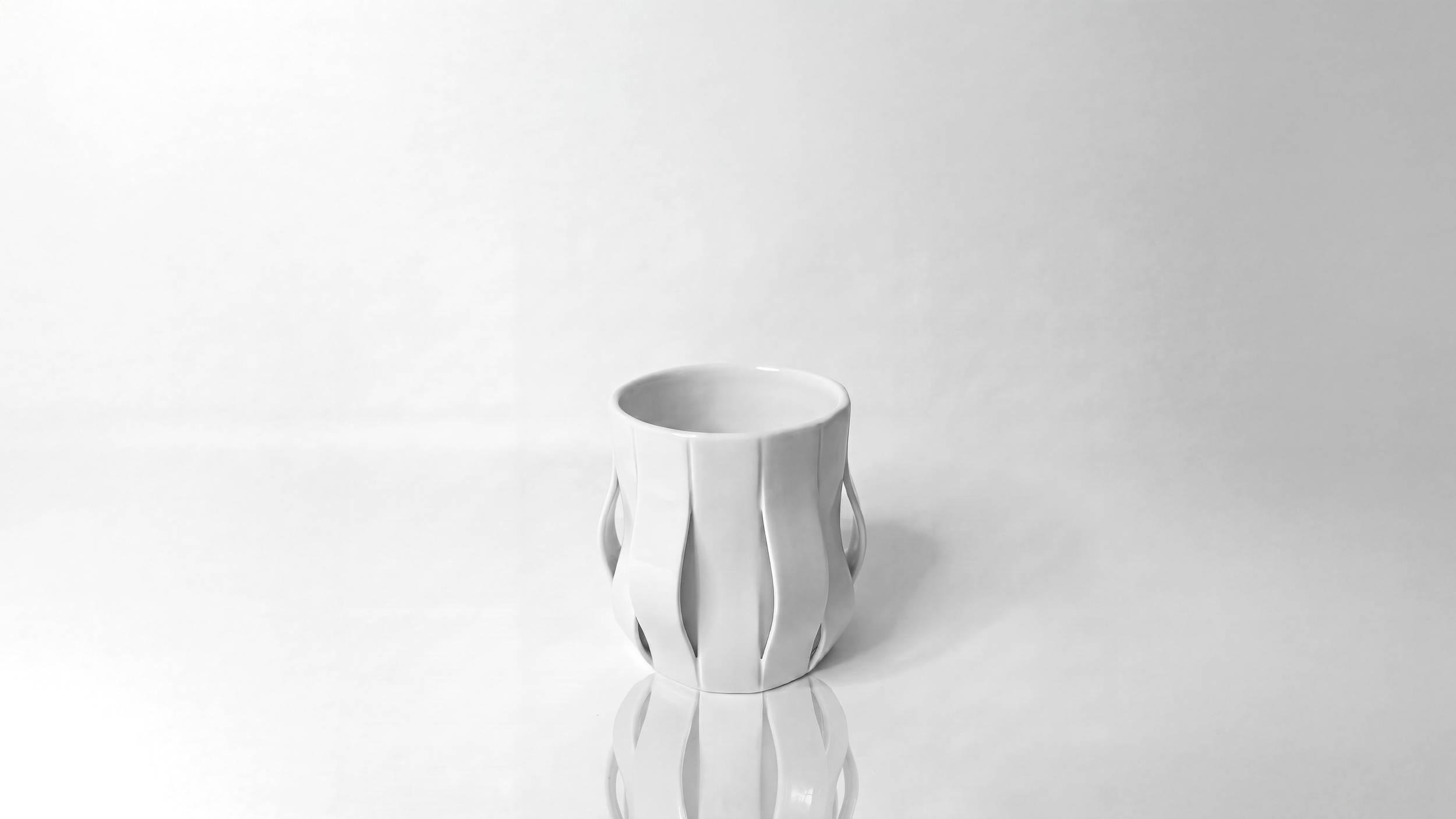 Finger Wave Mug by Pheiffer — a raised three-quarter view of the white glazed ceramic vessel, showing the open rim and the ribs curving away into handles
