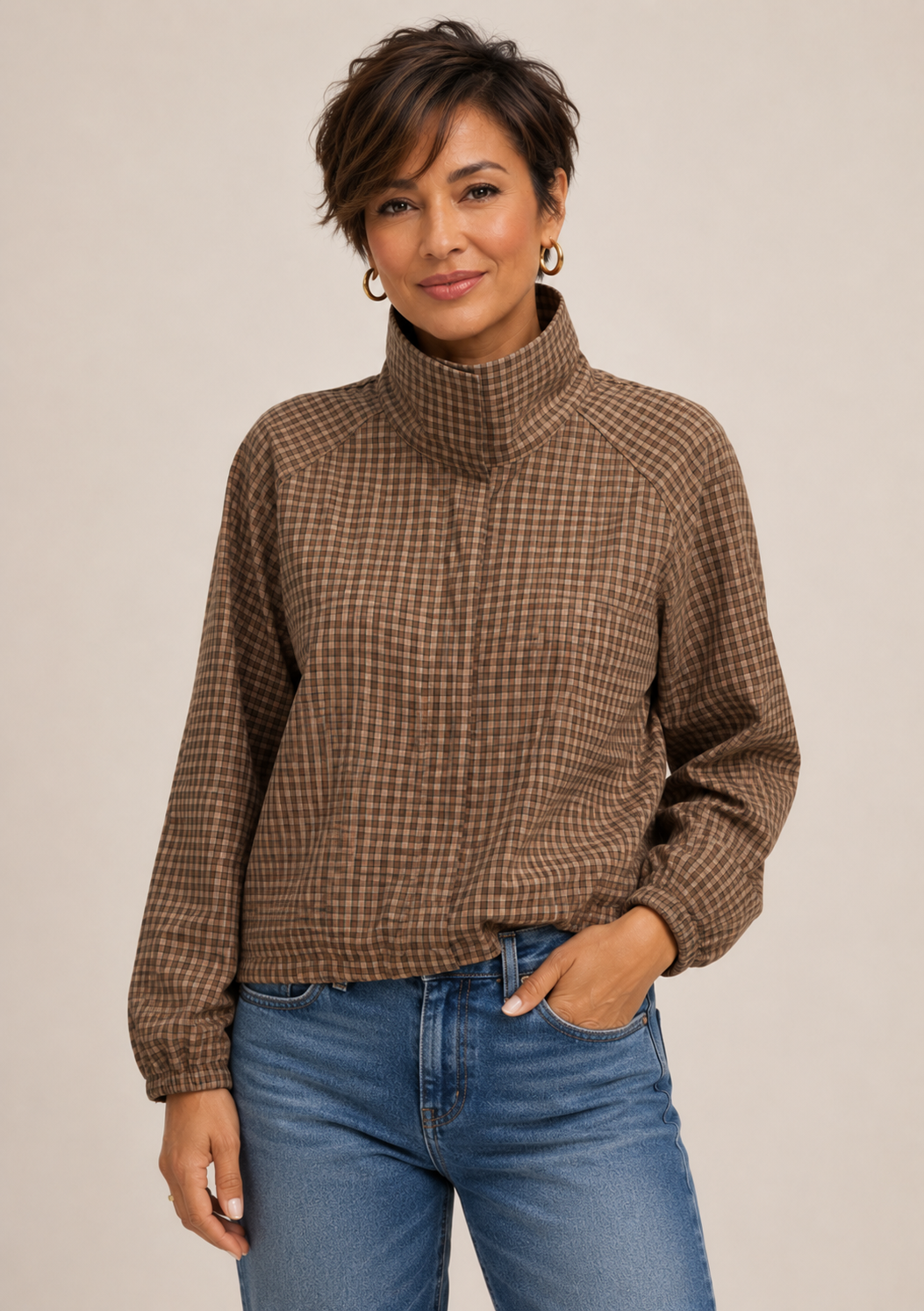 Woman in her 50s wearing a plaid jacket with jeans.