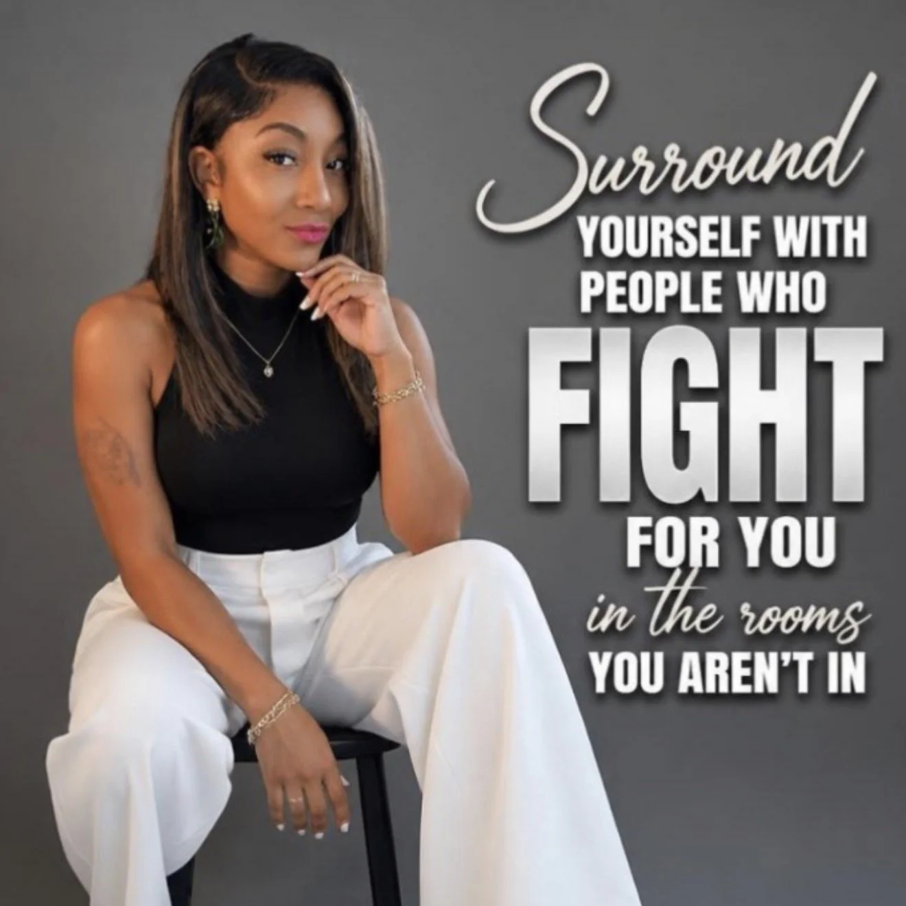 A woman sitting on a stool wearing a black sleeveless top and white wide-legged pants, with long brown hair, earrings, and a necklace, with a serious expression. Overlaid on the right side of the image is motivational text that reads: 'Surround yourself with people who fight for you in the rooms you aren't in.'