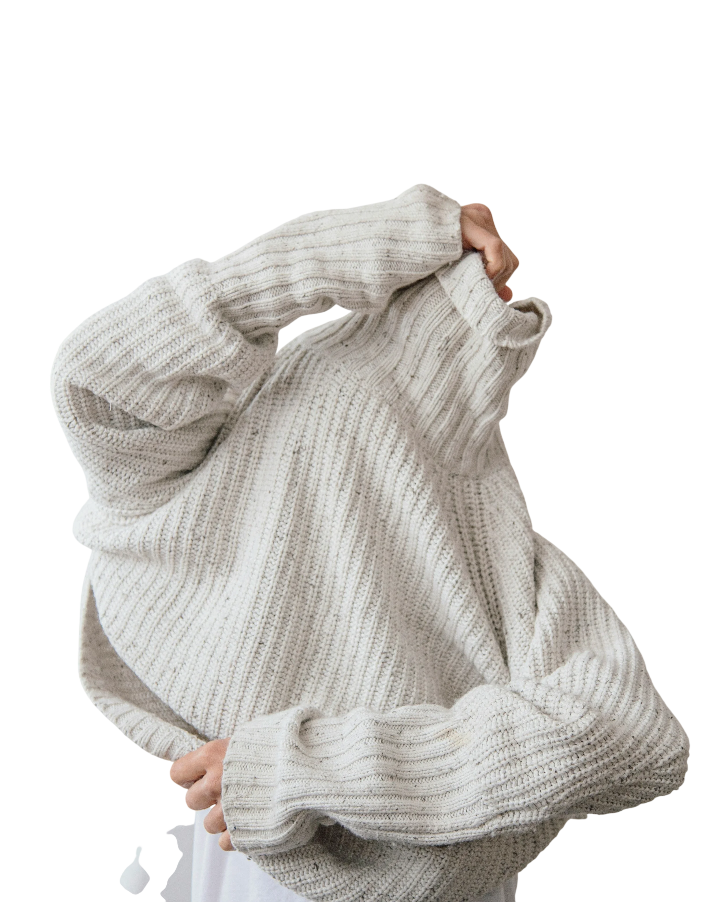 Close-up of a person wearing an oversized cream-colored, chunky ribbed knit sweater that is pulled over their face, hiding it, against a plain background.