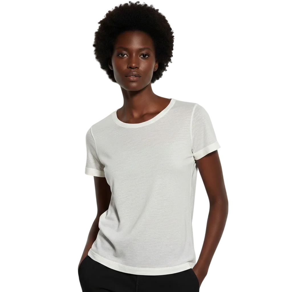 A woman with natural curly hair wearing a white t-shirt and black pants, standing against a neutral background.