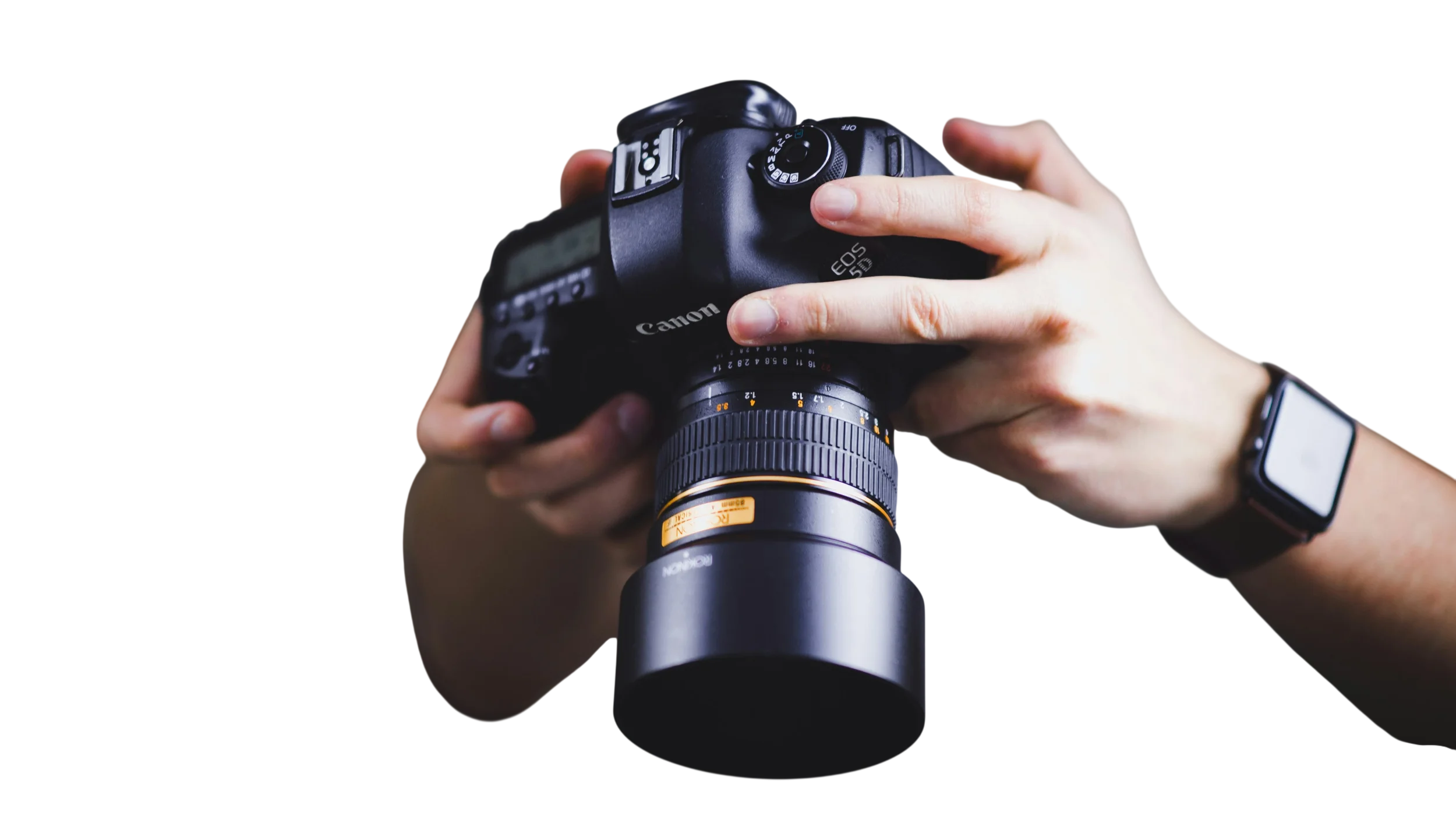 A person holding a Canon EOS camera with a zoom lens, wearing a smartwatch on their left wrist.