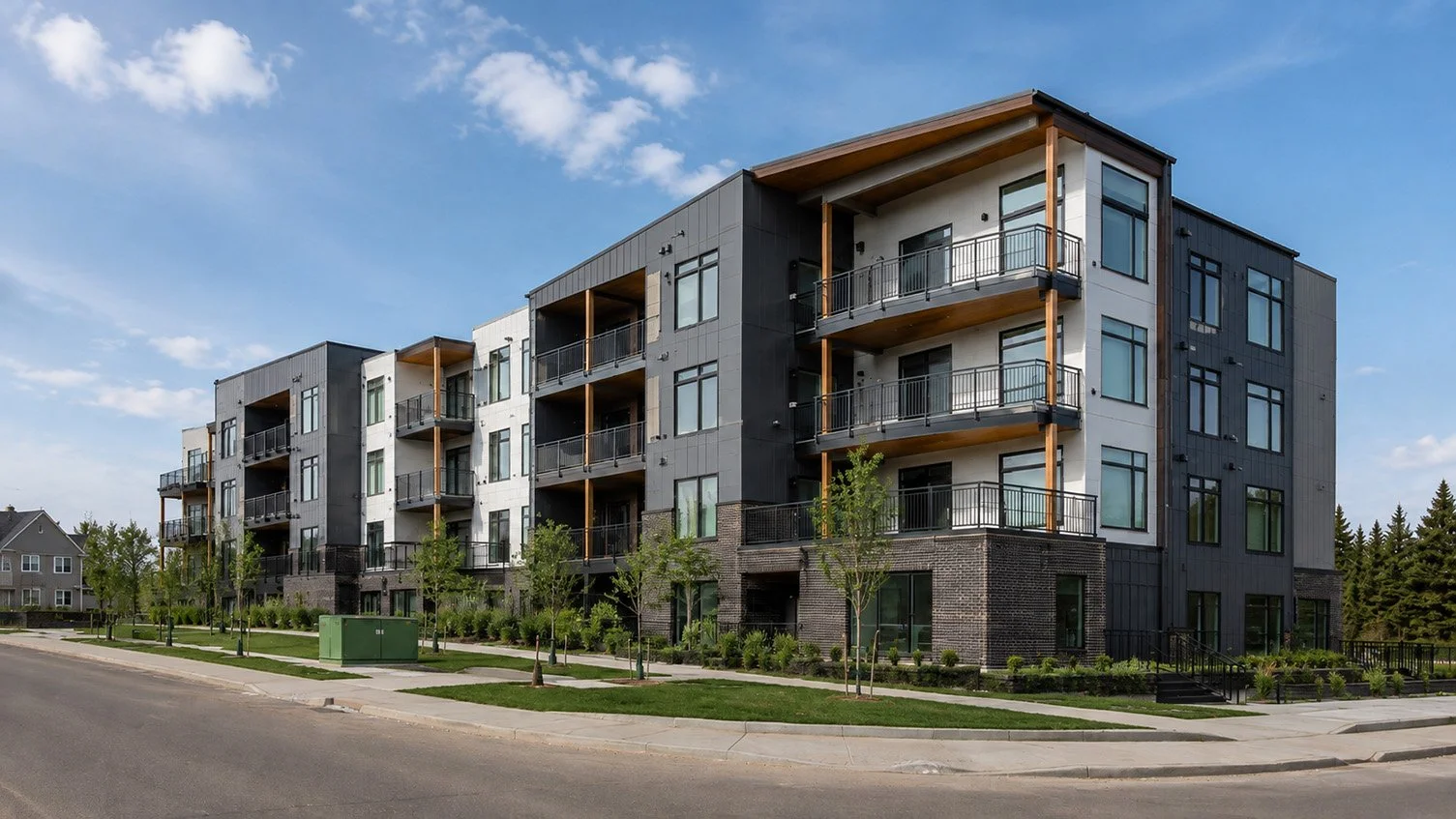 Modern multi-story apartment building with balconies, black and white facade, surrounded by trees and green landscaping, under a blue sky.