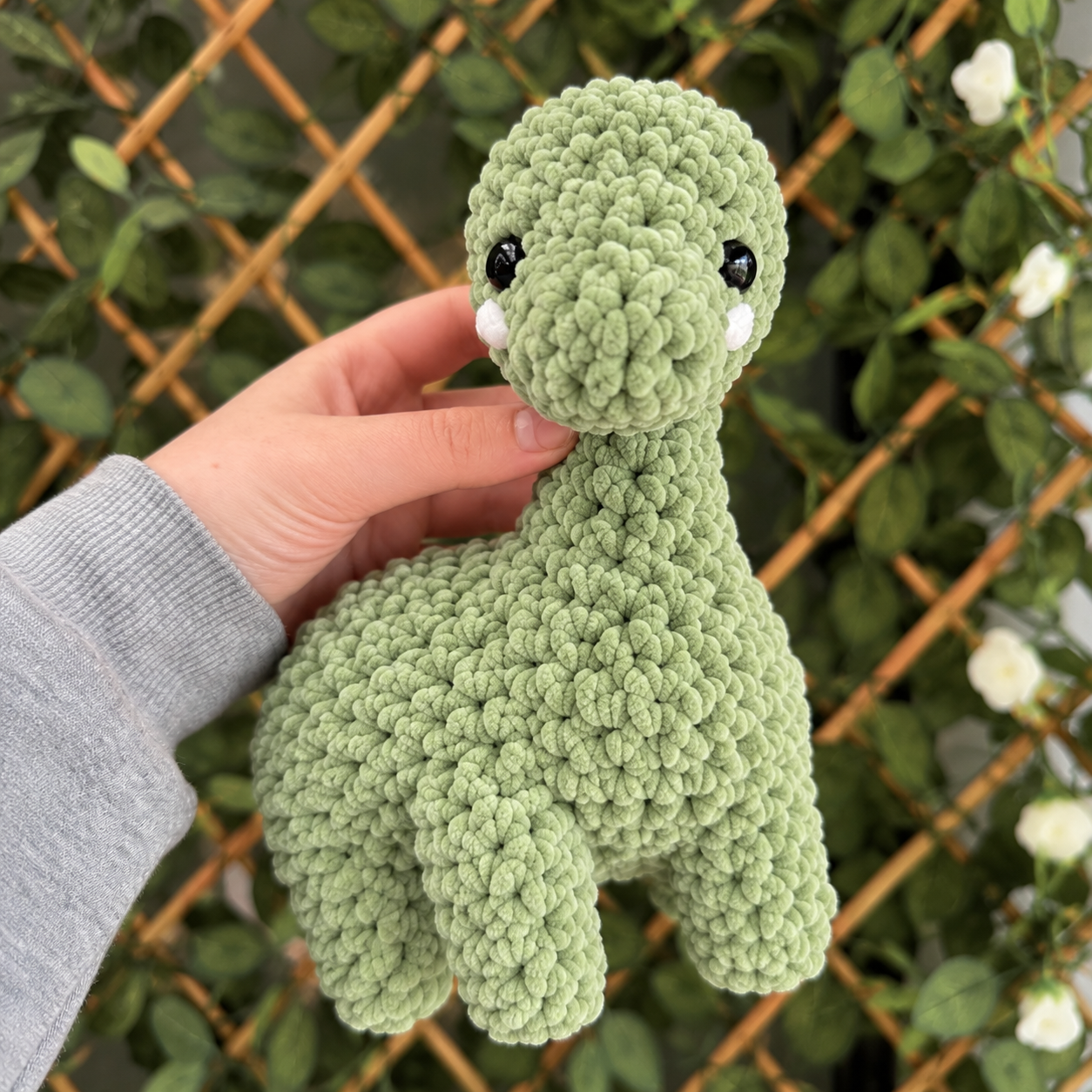 Handmade Plush Dinosaur in a Garden Setting.png