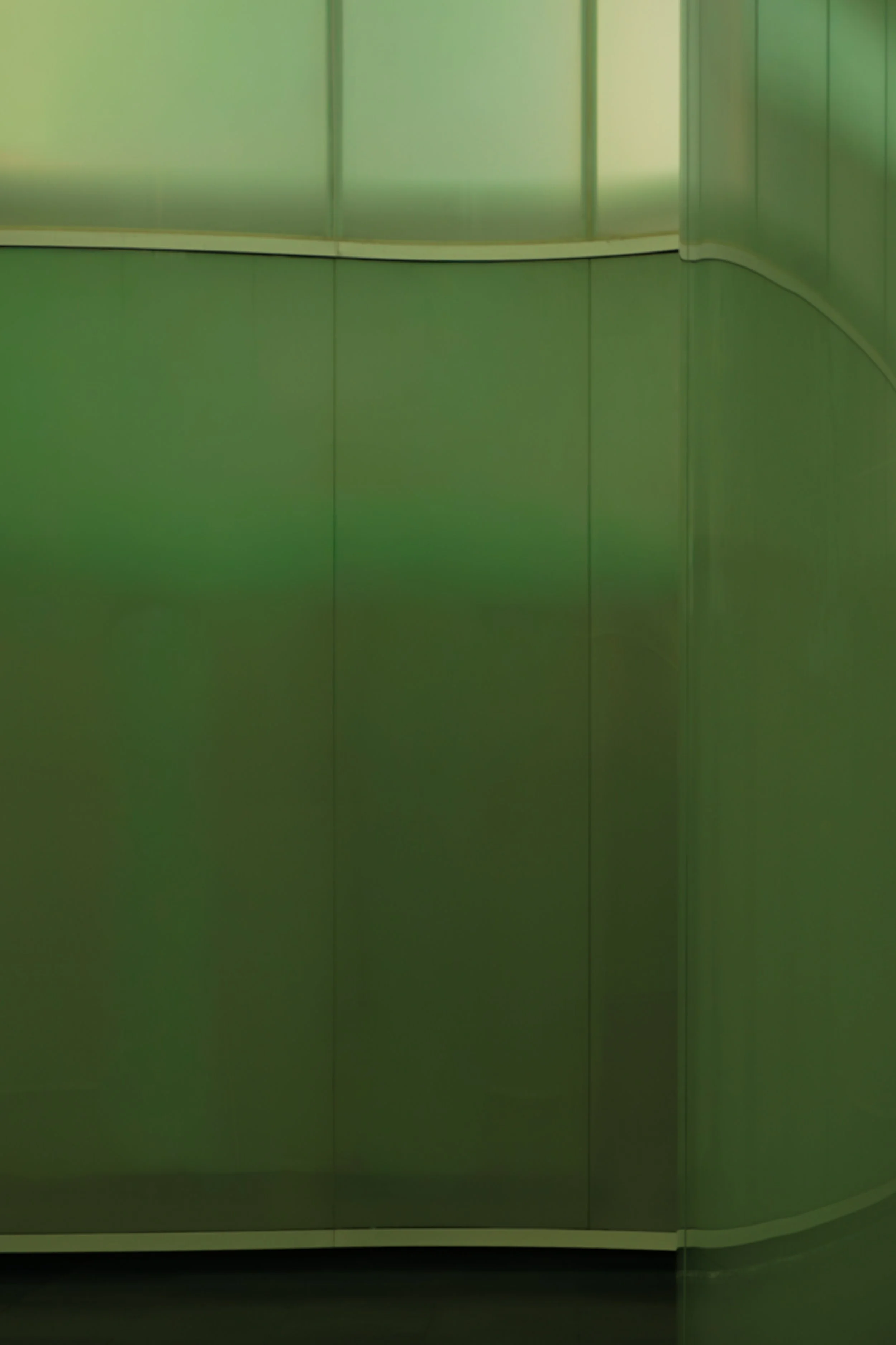 Green metallic elevator interior with curved walls and a horizontal white trim, no visible buttons or controls.