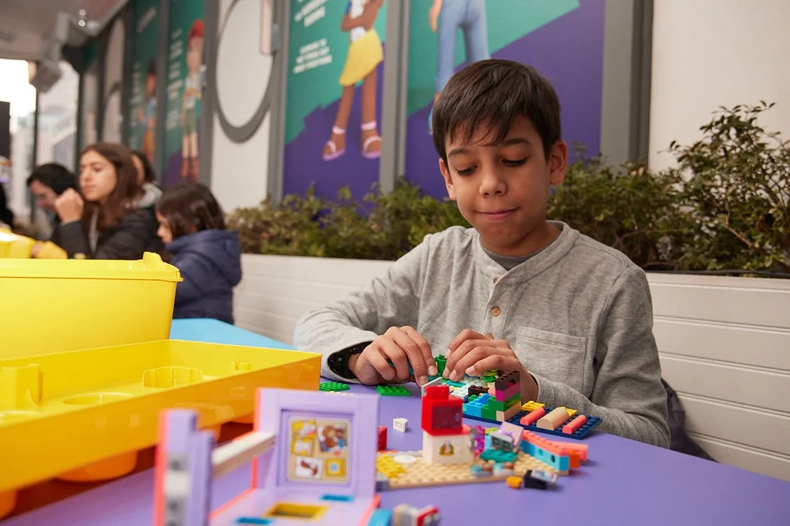 A boy building with colorful LEGO bricks at a table at the LEGO Friends Diner.
