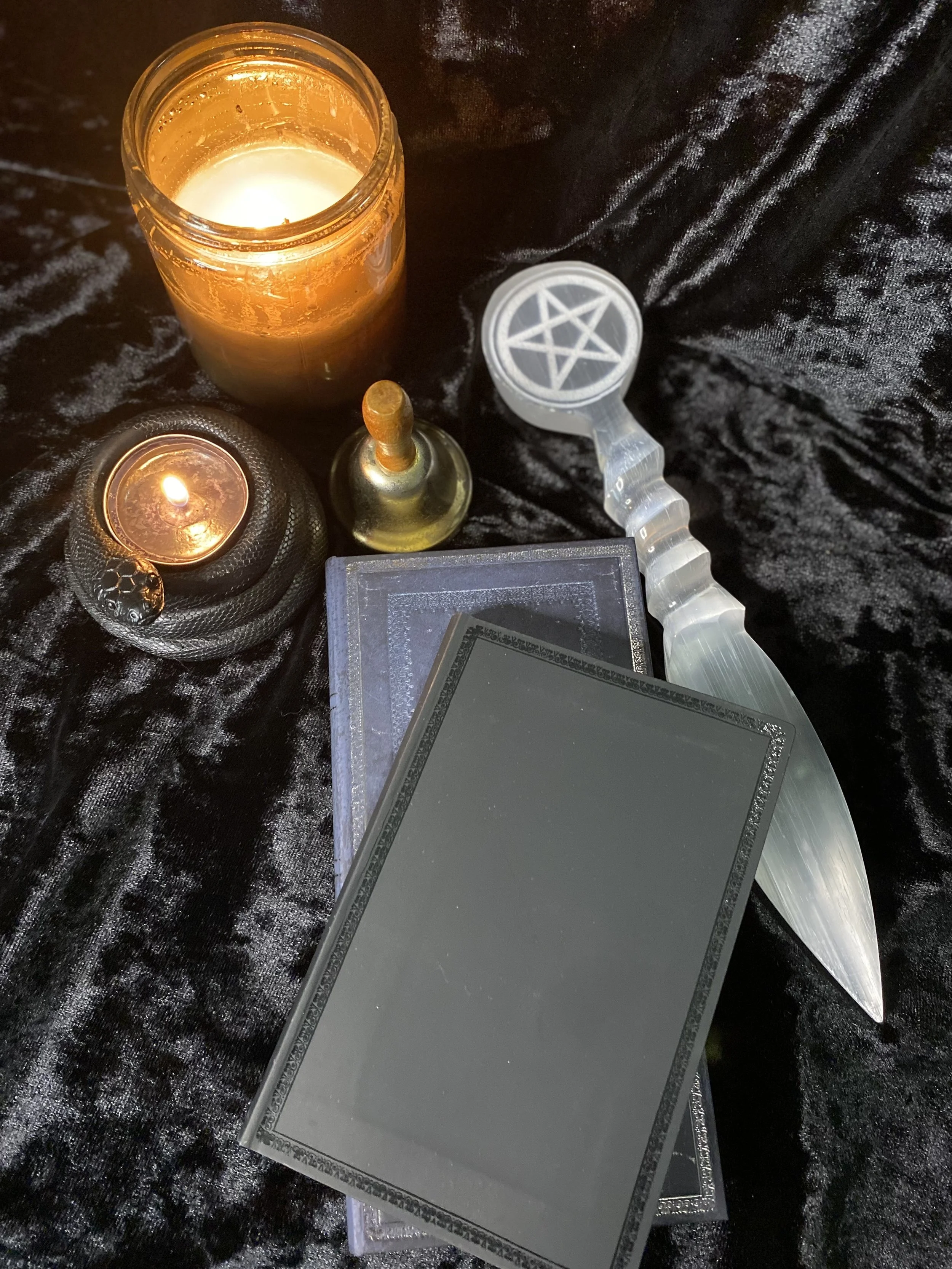 A black surface with candles, tarot cards, and a pentagram dabber