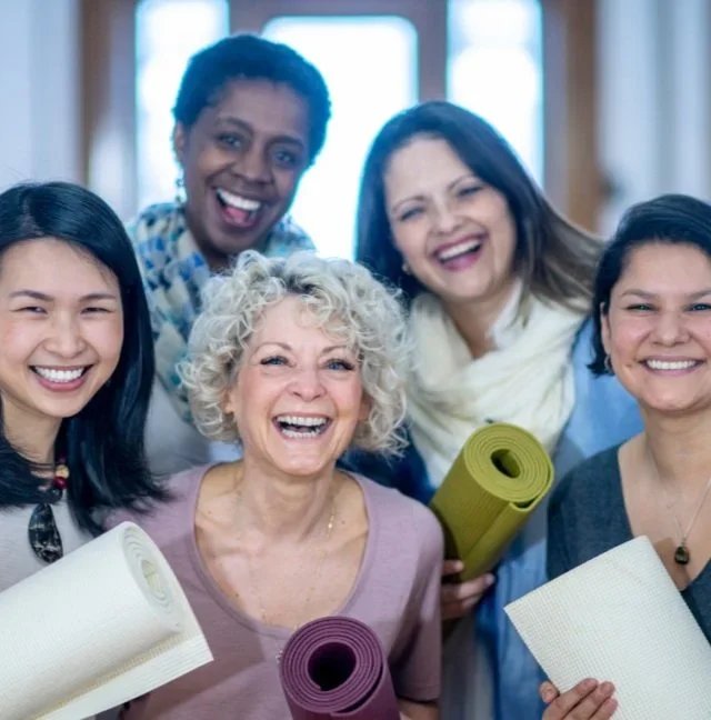 Group of smiling women of all ages holding exercise mats after pelvic floor therapy