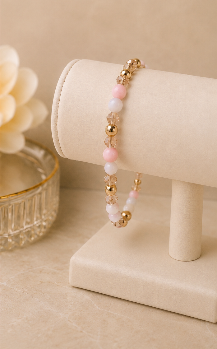 Handcrafted RéE beaded stretch bracelet with pink, white, clear, and gold beads displayed on a white jewelry stand.