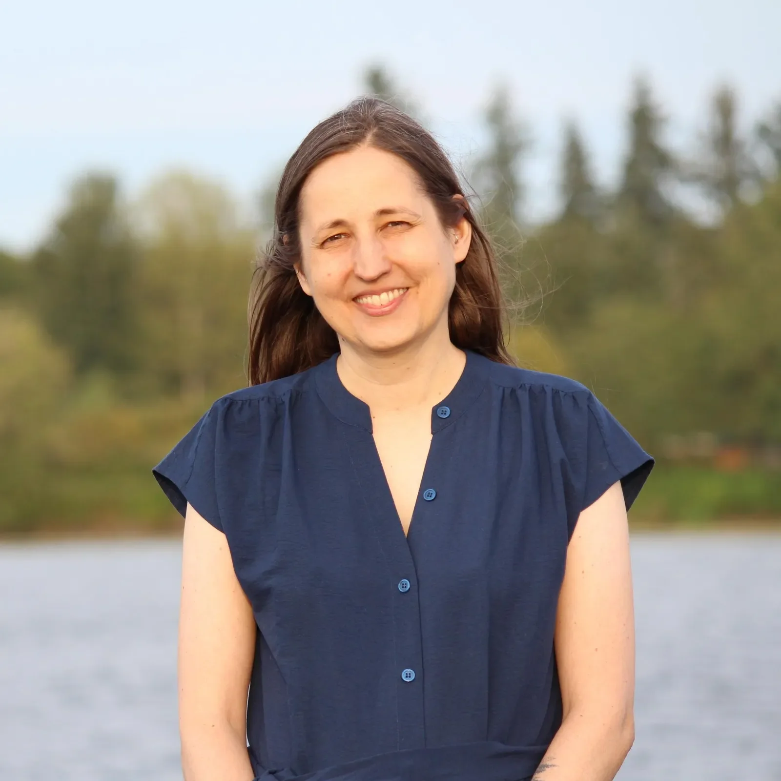 Tracy standing in front of a river and forest