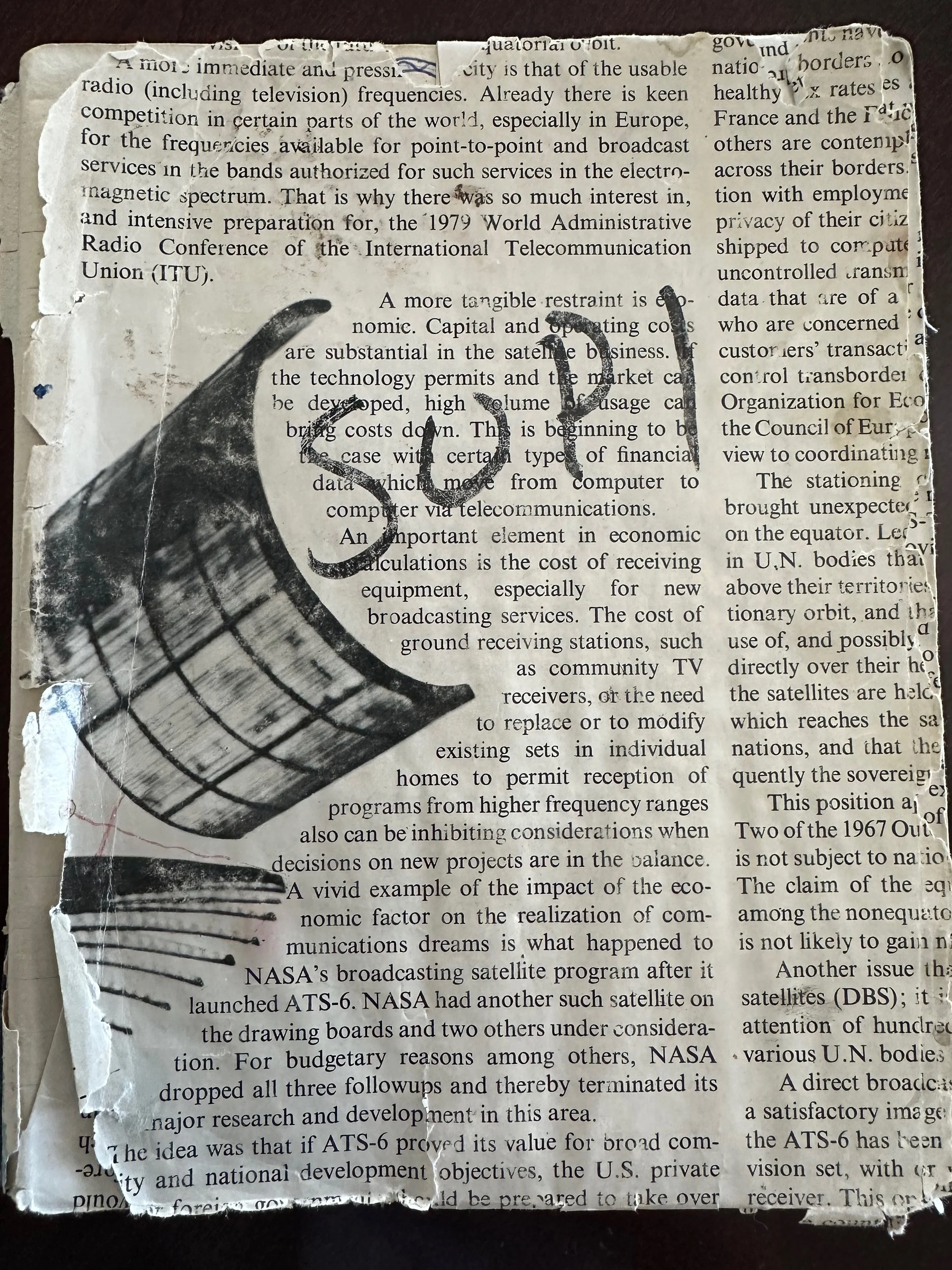 A torn, crumpled piece of newspaper with a black and white drawing of a satellite on it, partially covering printed text.