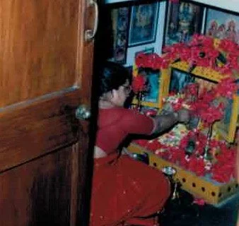 A woman arranging pink and red flowers in a display box.