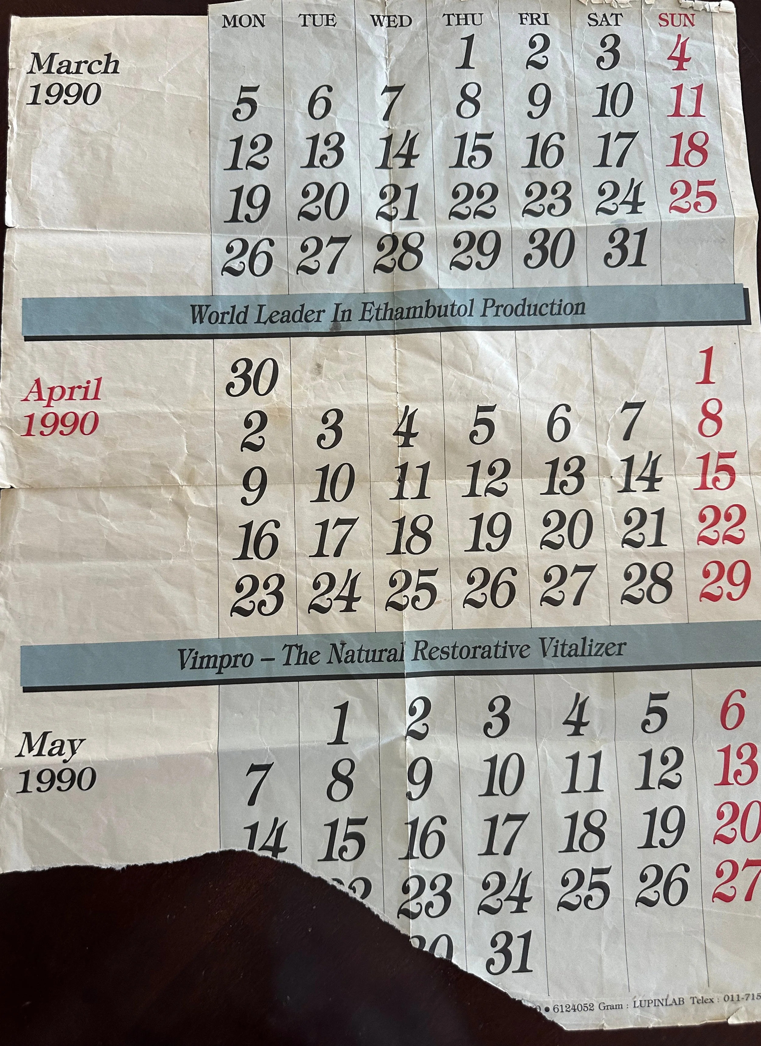 A torn calendar page displaying the month of March 1990 and part of April 1990. The calendar shows days of the week, with dates in black and Sundays in red. There are advertisements at the bottom, one promoting ethambutol production and another for a restorative vitality product called Vimpro.