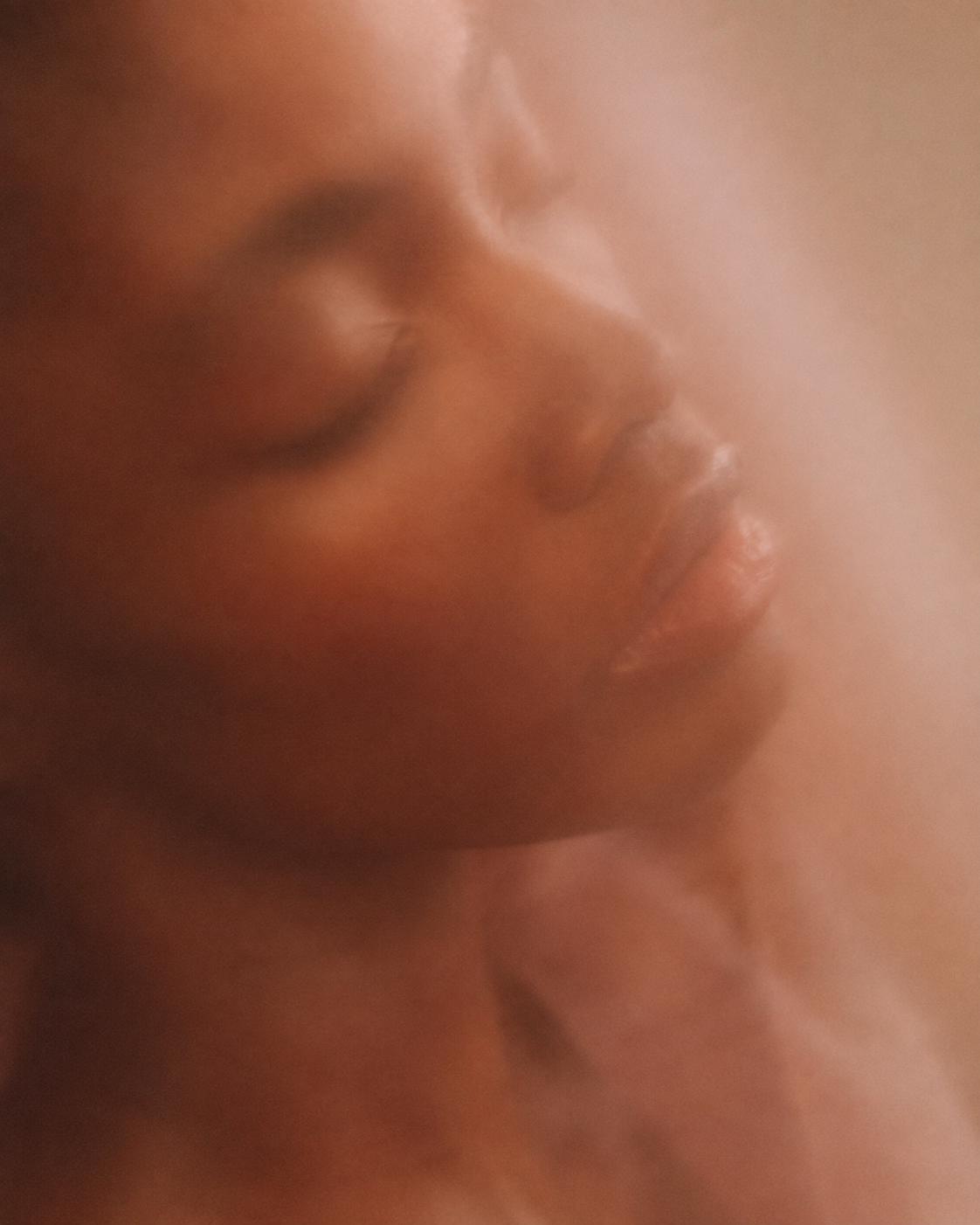 Close-up of a person's face with closed eyes and soft lighting, creating a peaceful and serene mood.