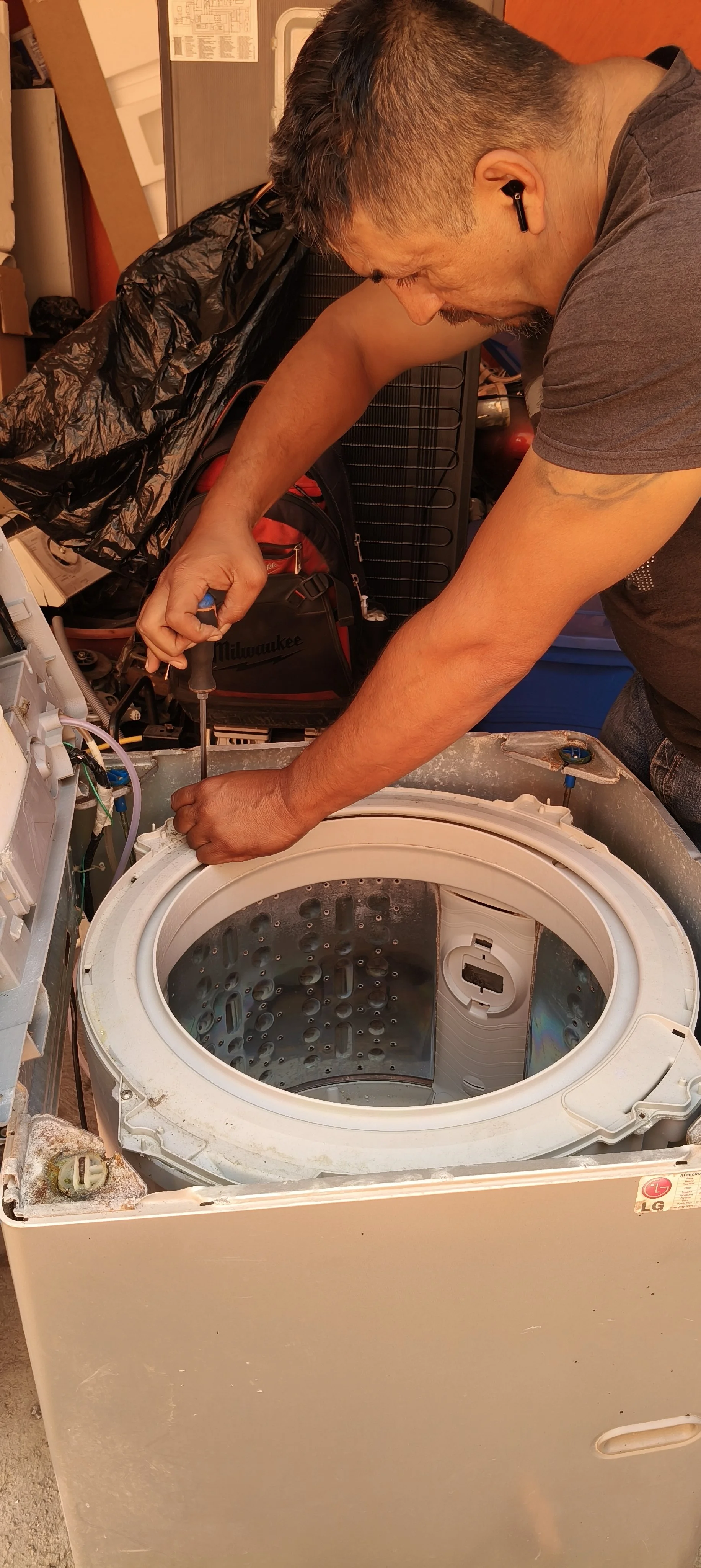 Técnico reparando una lavadora de carga superior con un destornillador